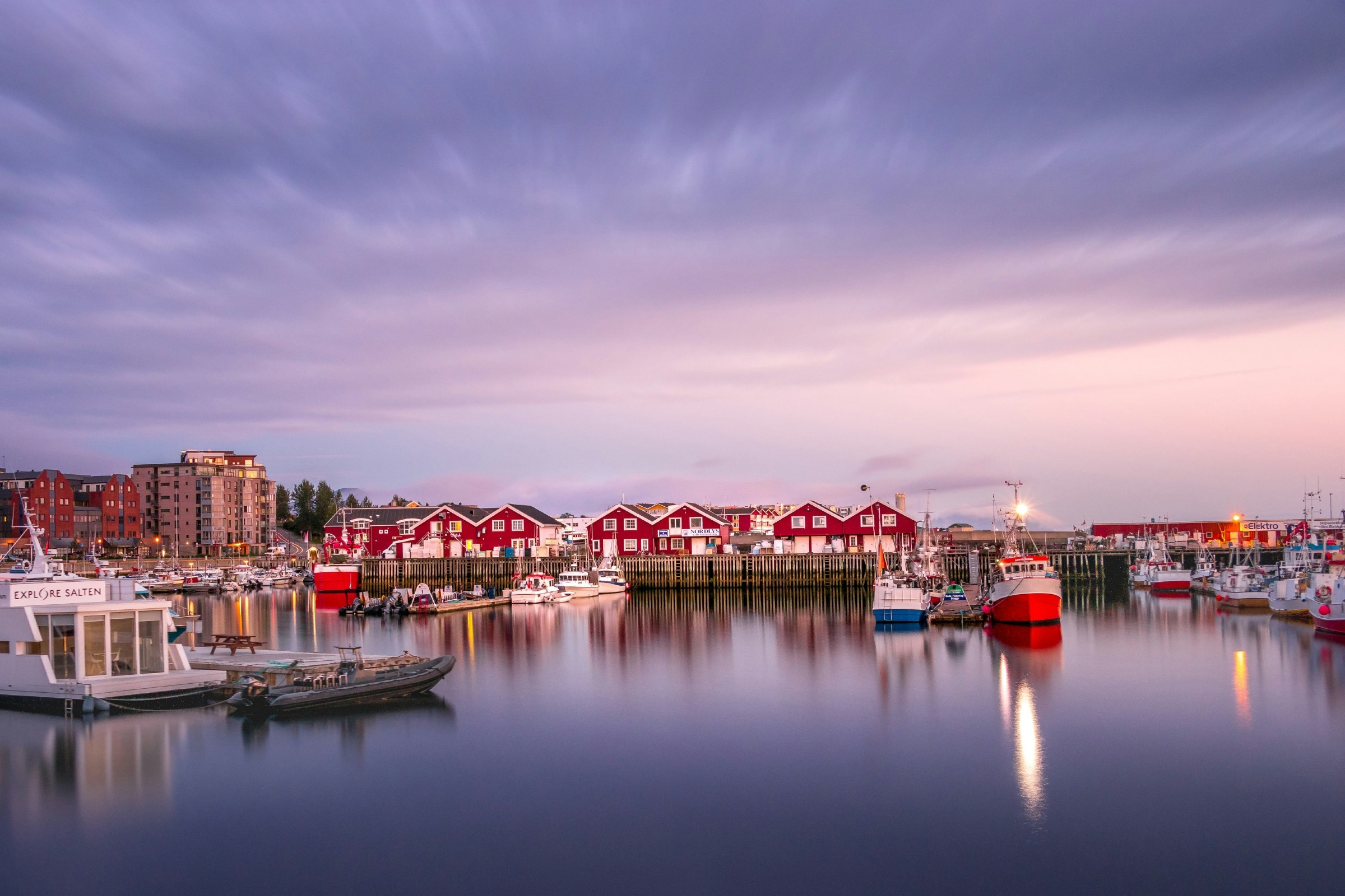 A row of red homes along the coast with a purple sunset in the background. 