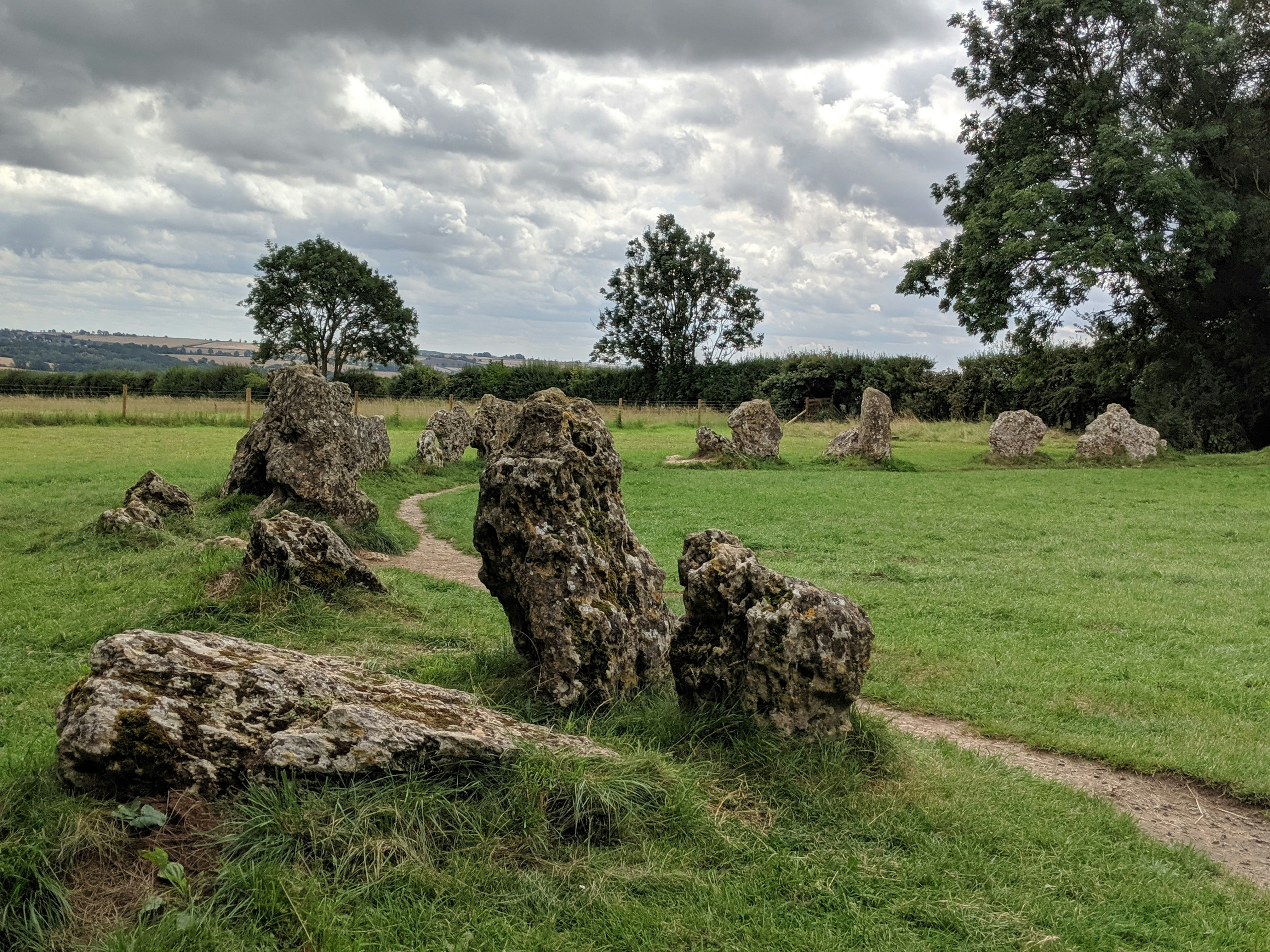 A group of standing stones in a green field on an overcast day.