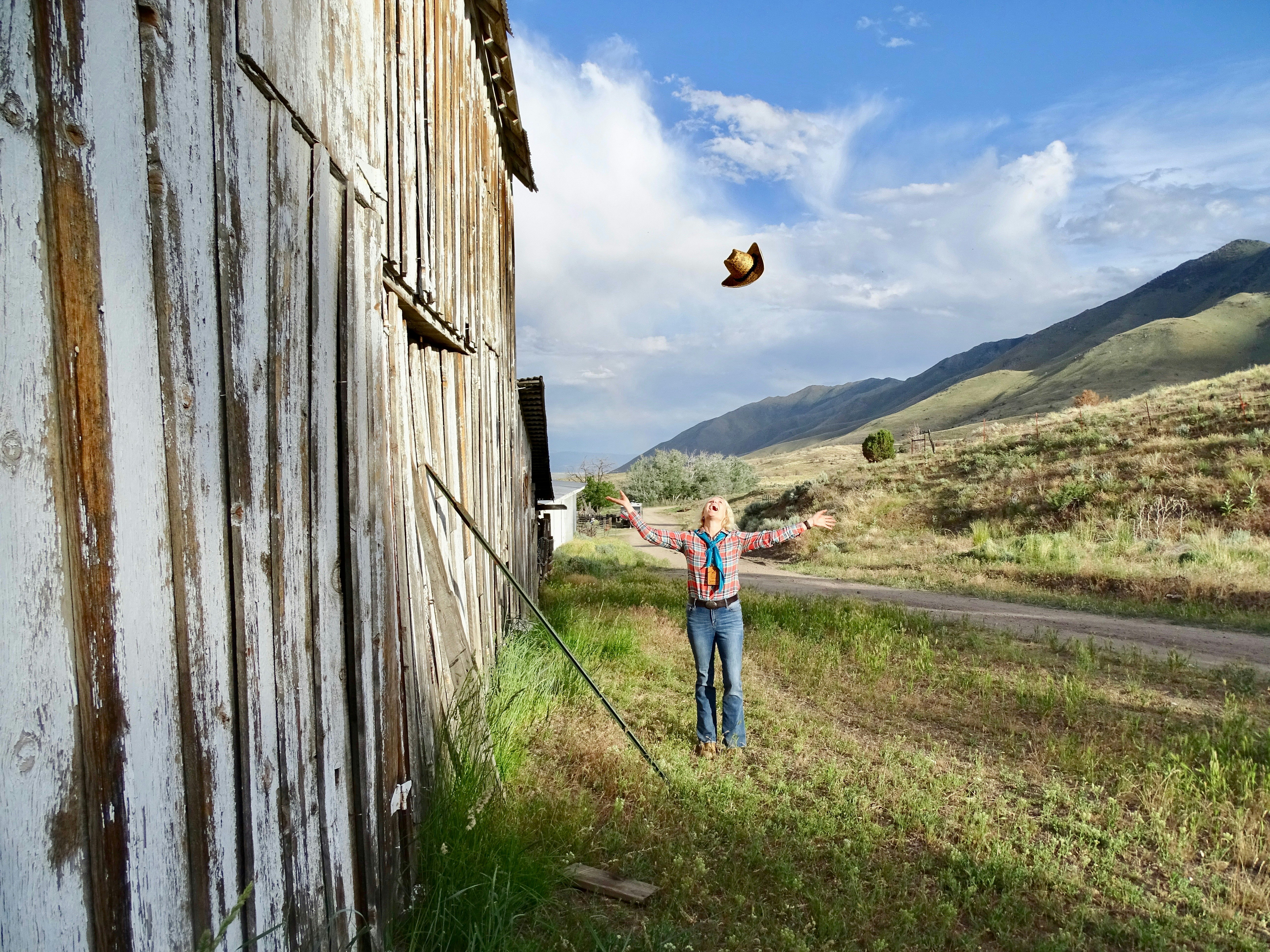 The author dressed in blue jeans and a plaid shirt, next to a faded barn wall