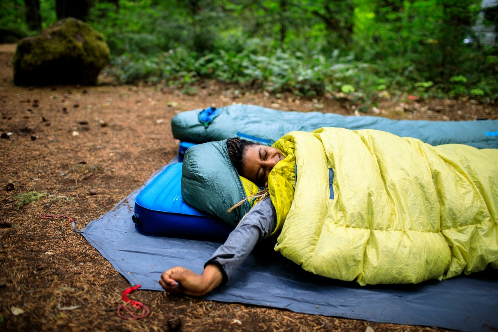 A woman stretches from inside a sleeping bag