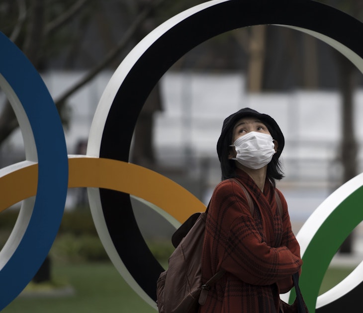 A woman wearing a face mask walks past the Olympic rings in front of the new National Stadium, the main stadium for the upcoming Tokyo 2020 Olympic and Paralympic Games, on February 26, 2020 in Tokyo, Japan. Concerns that the Tokyo Olympics may be postponed or cancelled are increasing as Japan confirms 862 cases of Coronavirus (COVID-19) and as some professional sporting contests are being called off or rescheduled