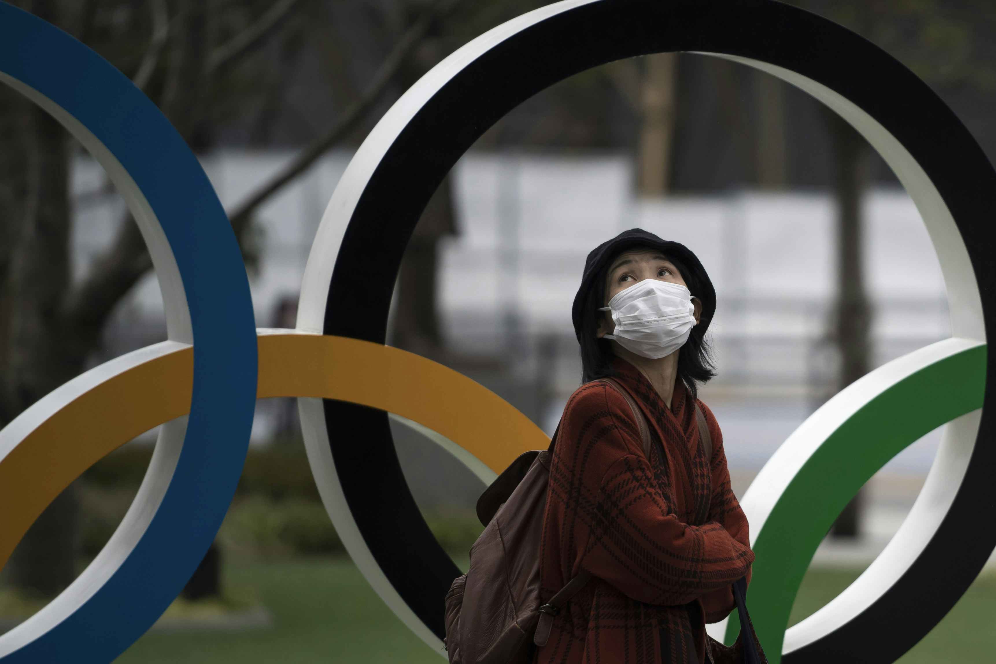 A woman wearing a face mask walks past the Olympic rings in front of the new National Stadium, the main stadium for the upcoming Tokyo 2020 Olympic and Paralympic Games, on February 26, 2020 in Tokyo, Japan. Concerns that the Tokyo Olympics may be postponed or cancelled are increasing as Japan confirms 862 cases of Coronavirus (COVID-19) and as some professional sporting contests are being called off or rescheduled