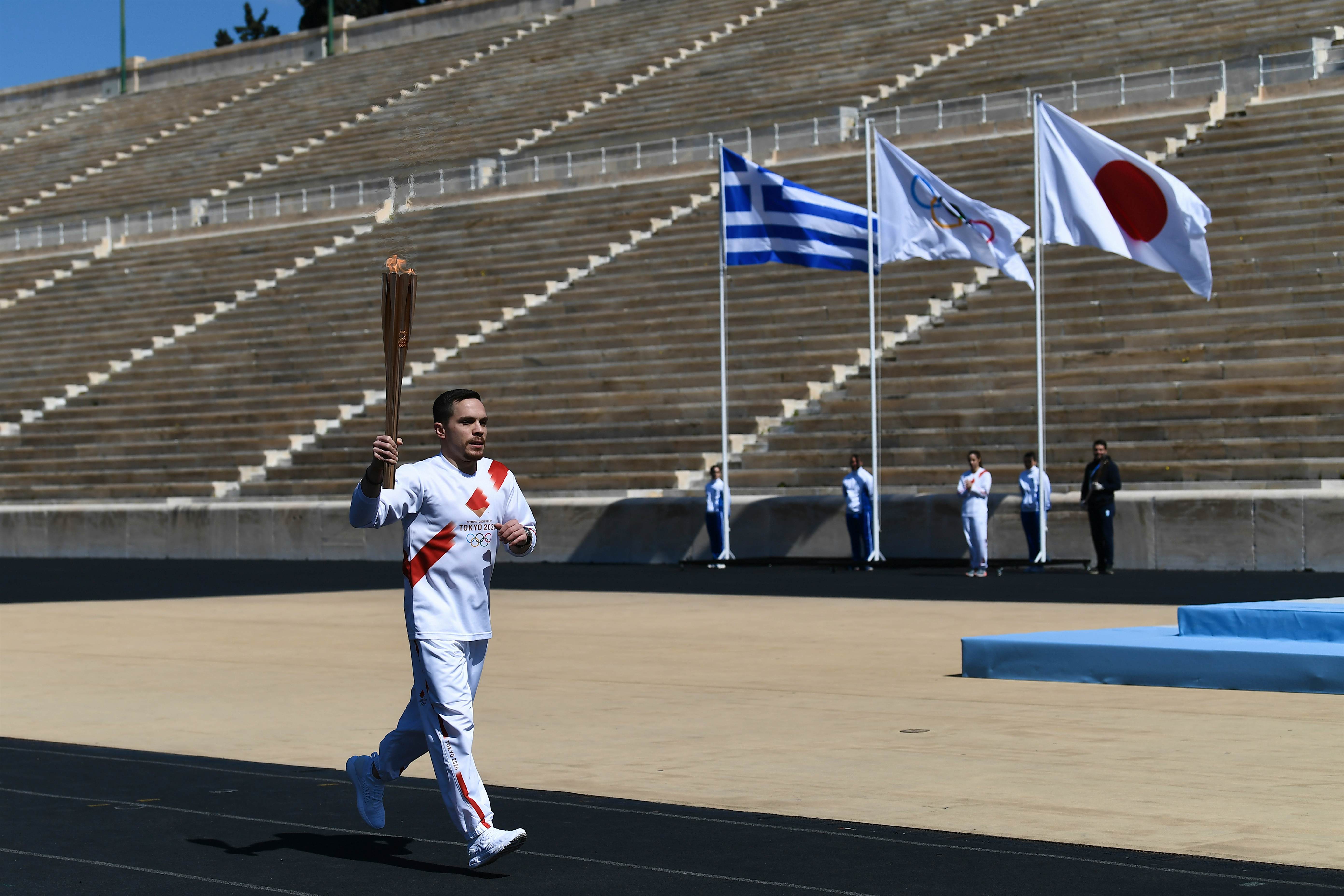 Tokyo Olympics torch relay RM.jpg An athlete carries the olympic torch during one of the last relays ahead of during the olympic flame handover ceremony for the 2020 Tokyo Summer Olympics, on March 19, 2020 in Athens. The ceremony is held behind closed doors as a preventive measure against the spread of the Covid-19 caused by the novel Coronavirus.