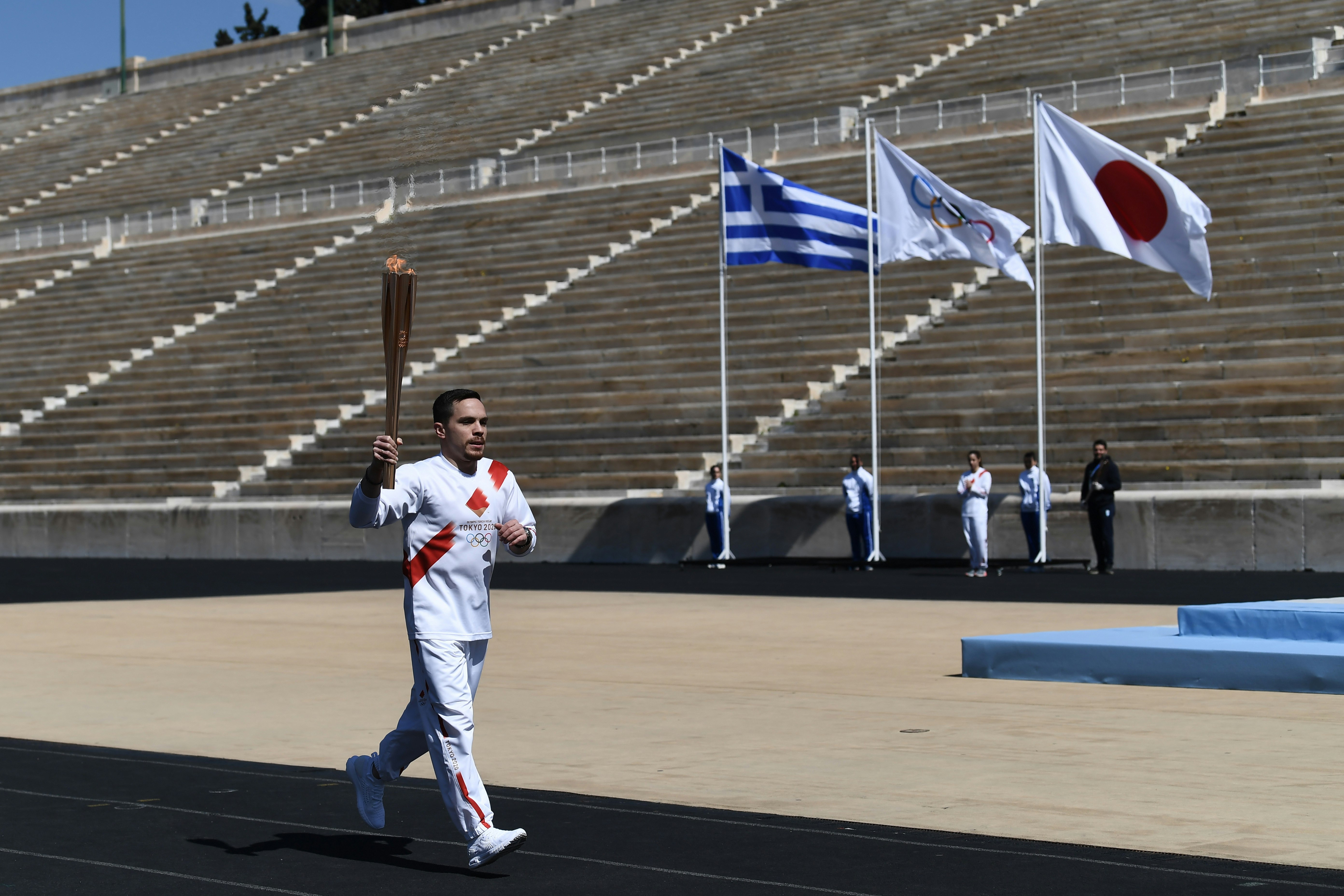 An athlete carries the olympic torch during one of the last relays ahead of during the olympic flame handover ceremony for the 2020 Tokyo Summer Olympics, on March 19, 2020 in Athens. The ceremony is held behind closed doors as a preventive measure against the spread of the Covid-19 caused by the novel Coronavirus. 