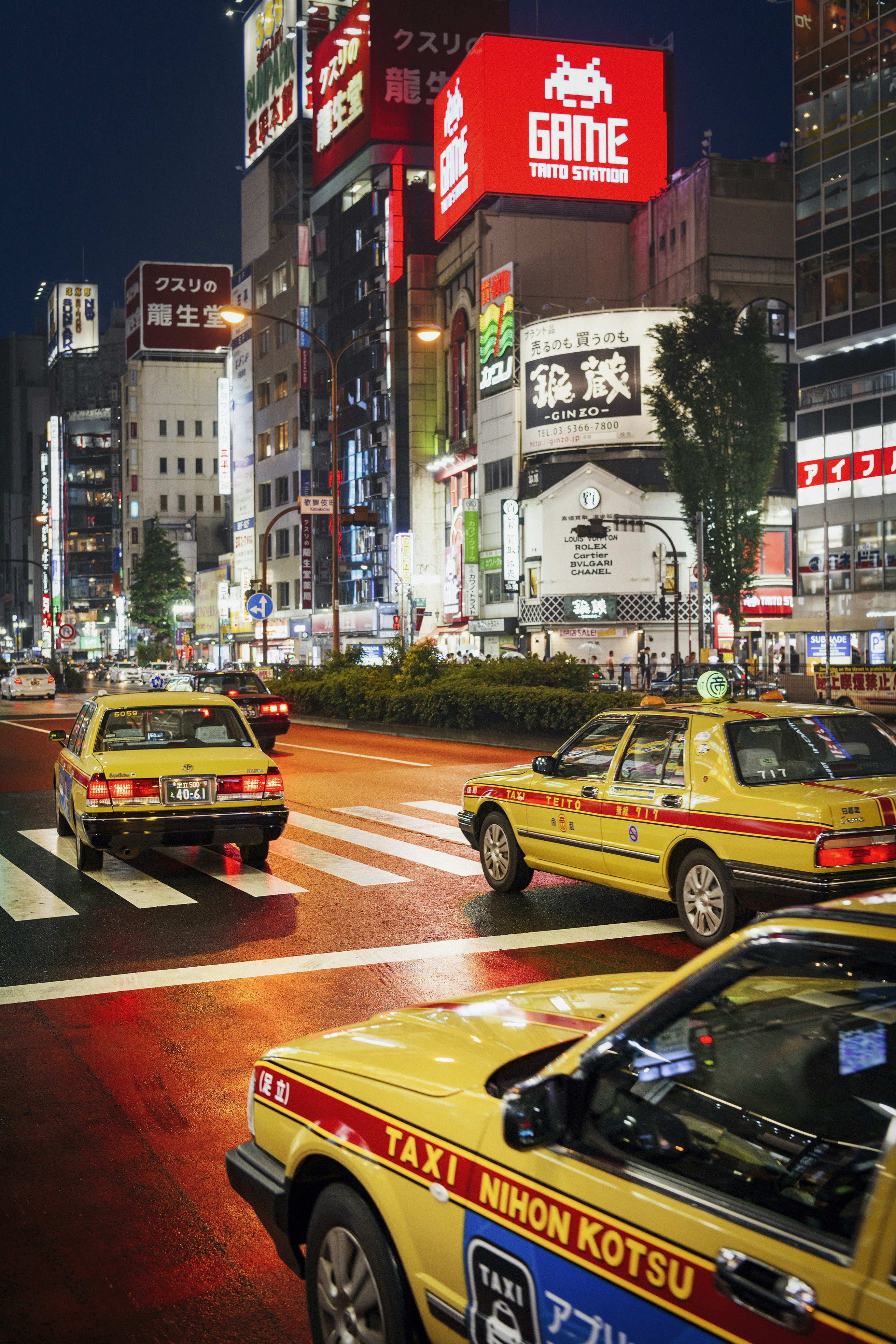 Taxis are making their way down a busy Tokyo street at night.