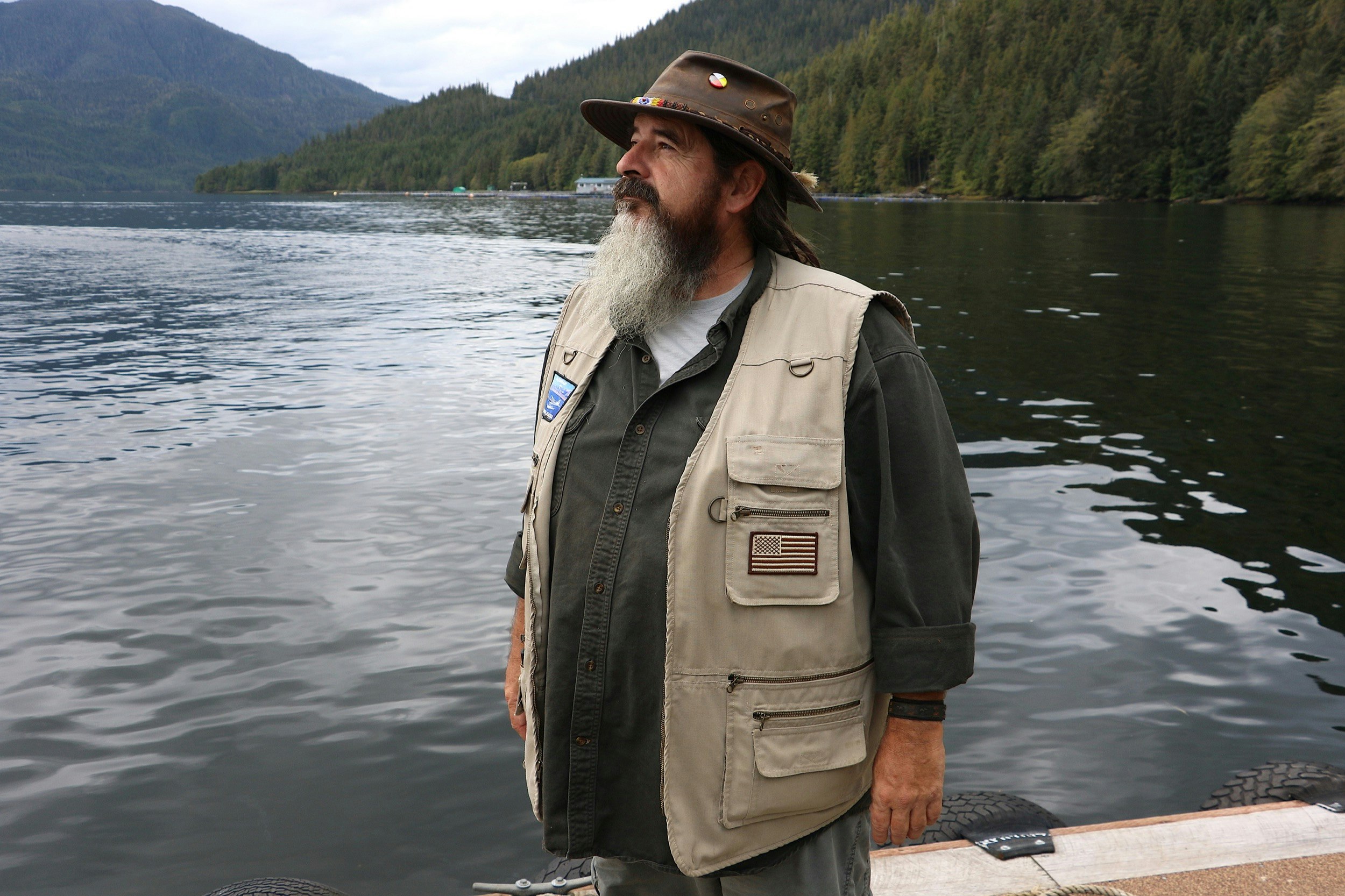 A guide with a long beard and a vest looks out over the landscape in Alaska's Tongass National Forest