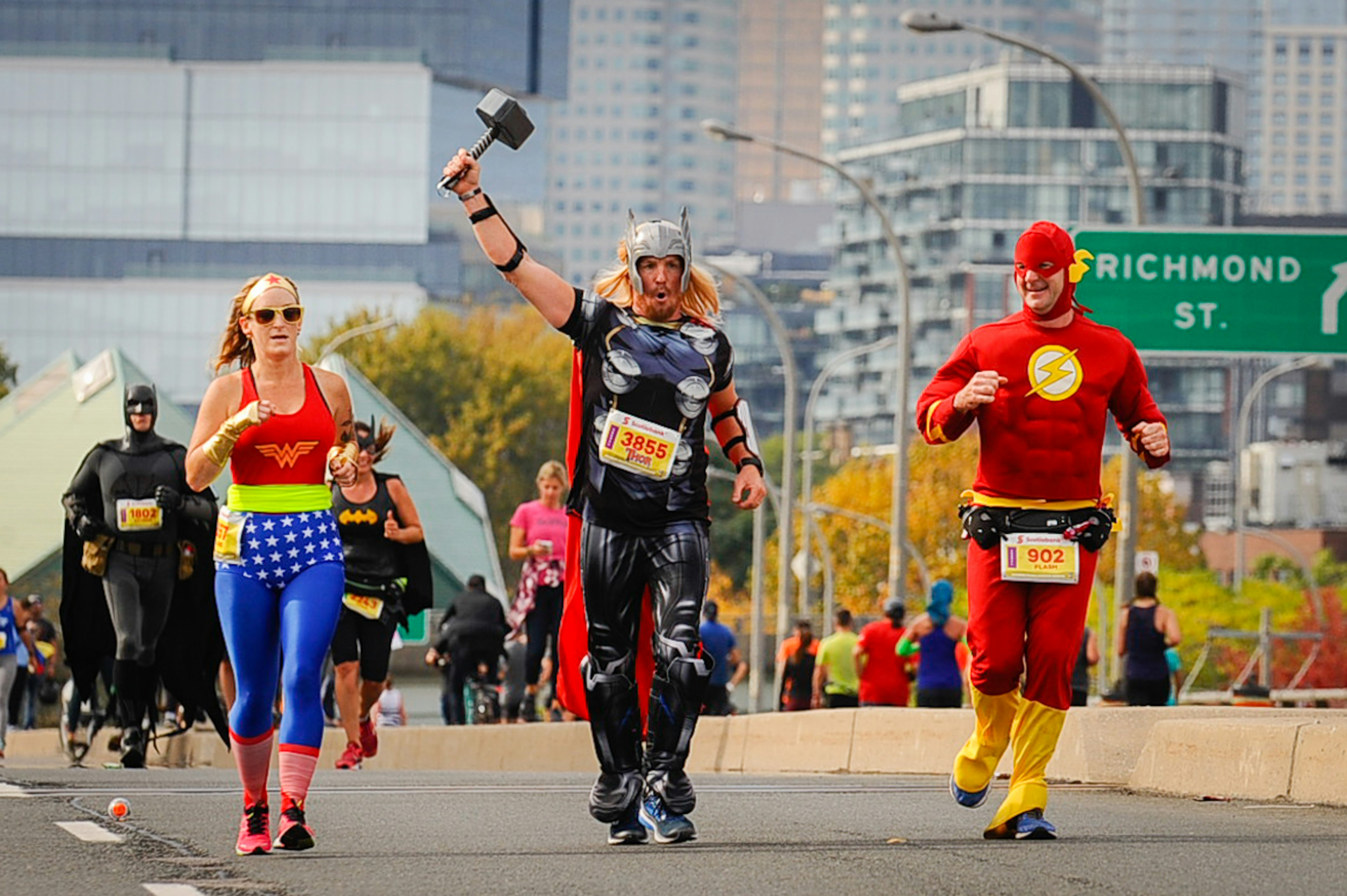 A trio of runners, one dressed as Wonder Woman, another dressed as Thor and the other dressed as the Flash run during the Toronto Waterfront Marathon