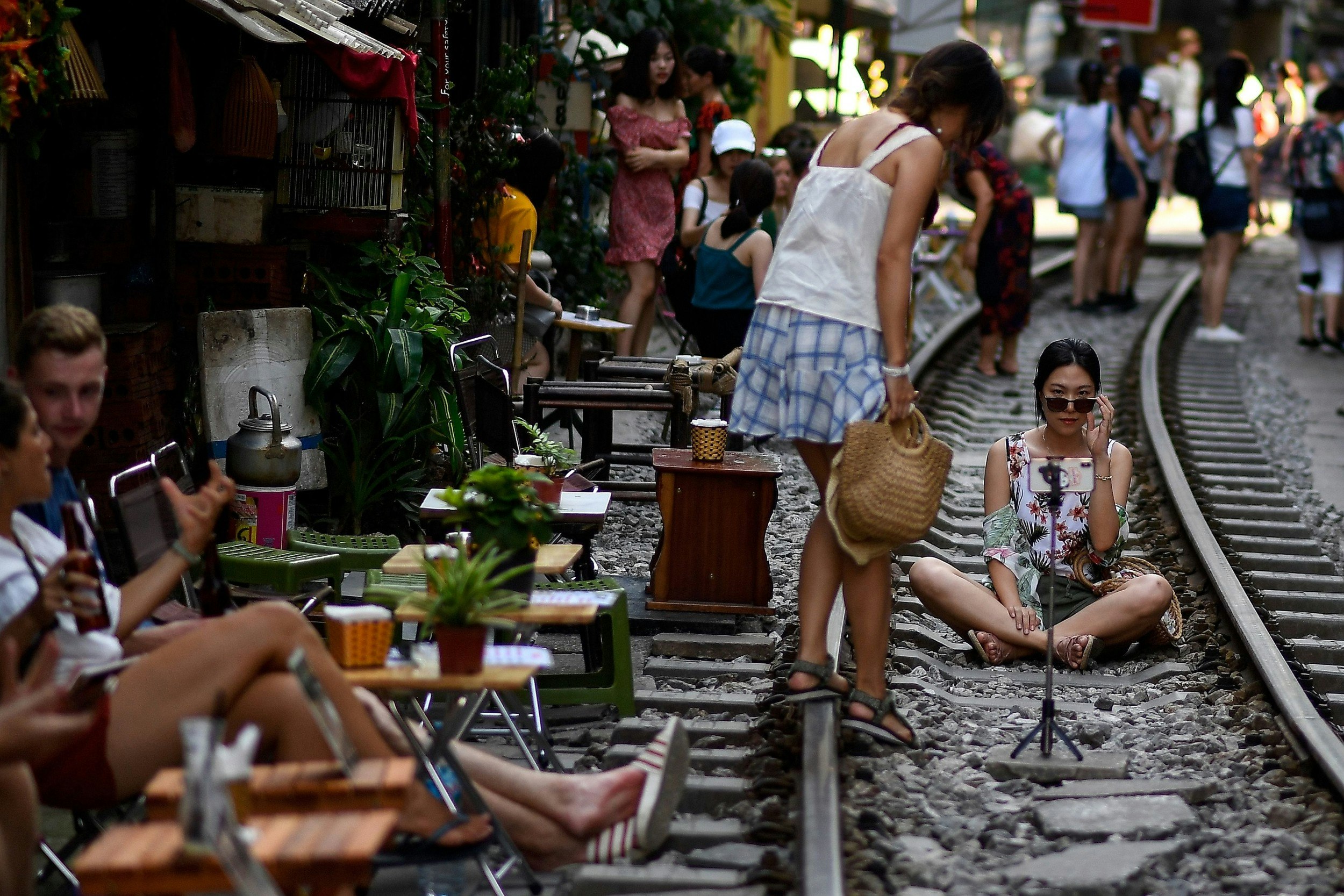 Women posing for a selfie on the railway track in Hanoi's Train Street and other people lining the street