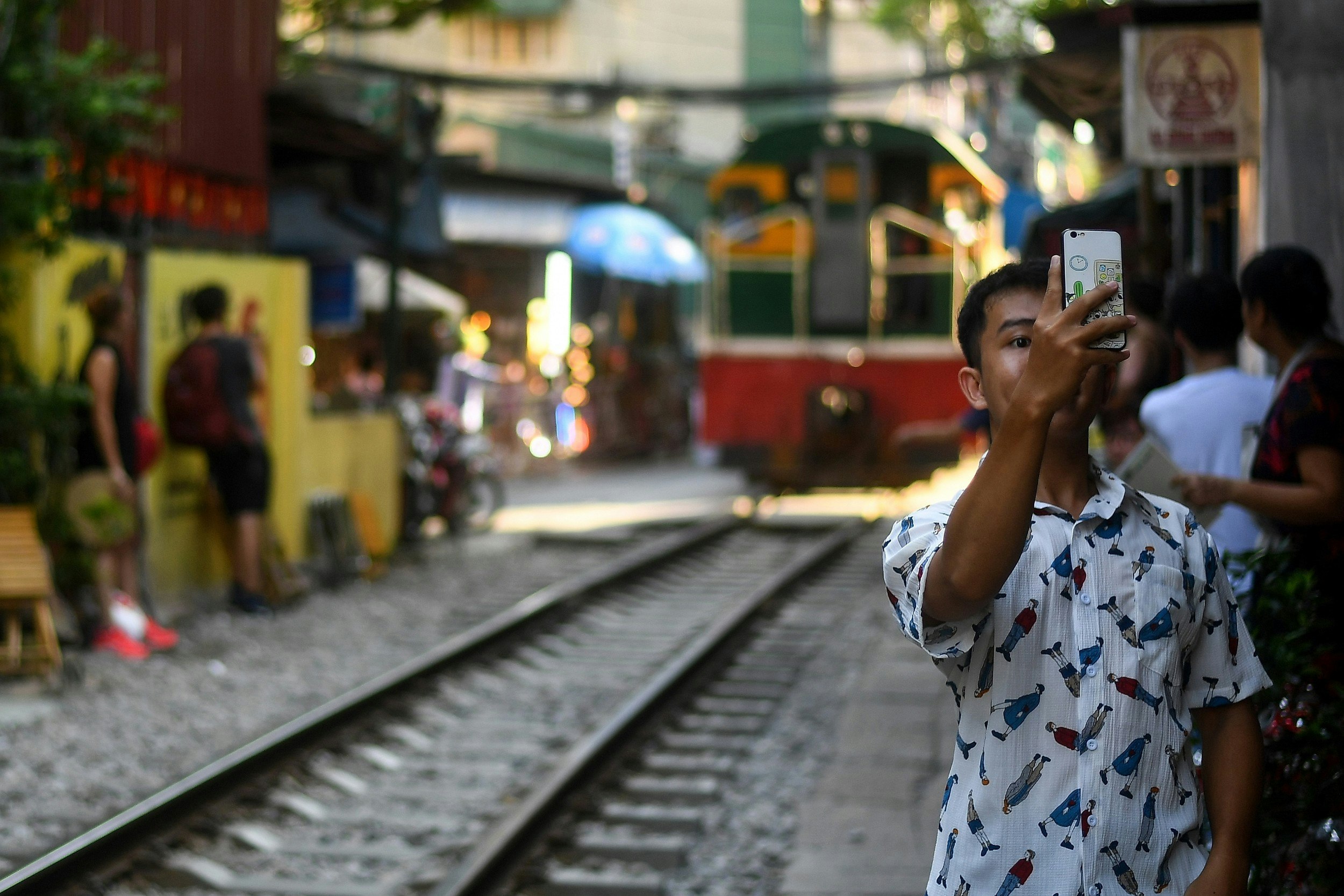 A man taking a selfie as the train approaches on the railway track in Hanoi's popular Train Street 