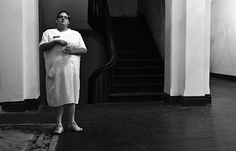 Trans-Allegheny-LunaticAsylum.jpg A woman in a white nurses uniform holds a bottle of water while staring directly at the camera; us haunted places