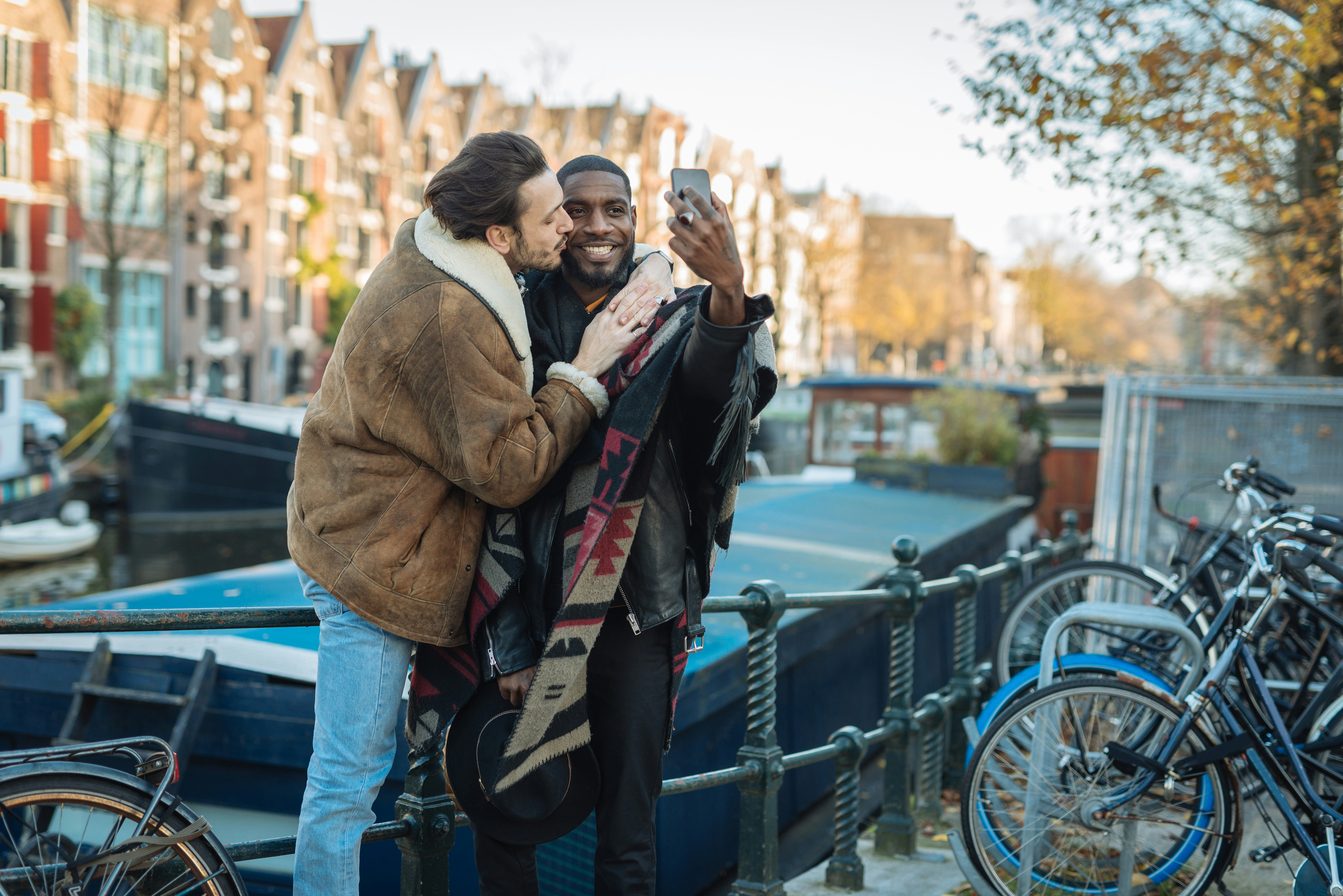 A couple pose for a selfie on the street in Amsterdam during late autumn