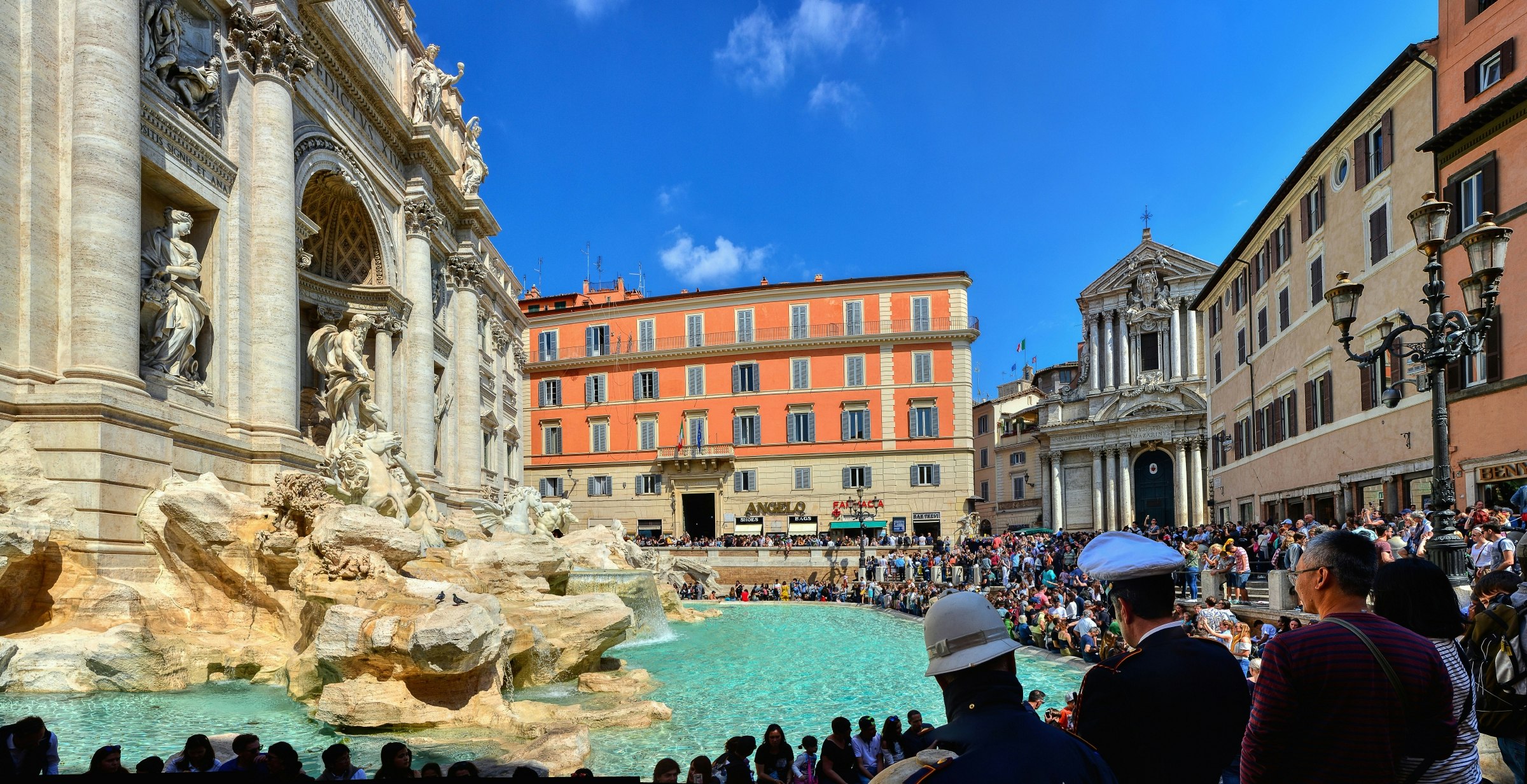 Crowd of tourists visiting the Fountain of Trevi in the historic district of Rome.