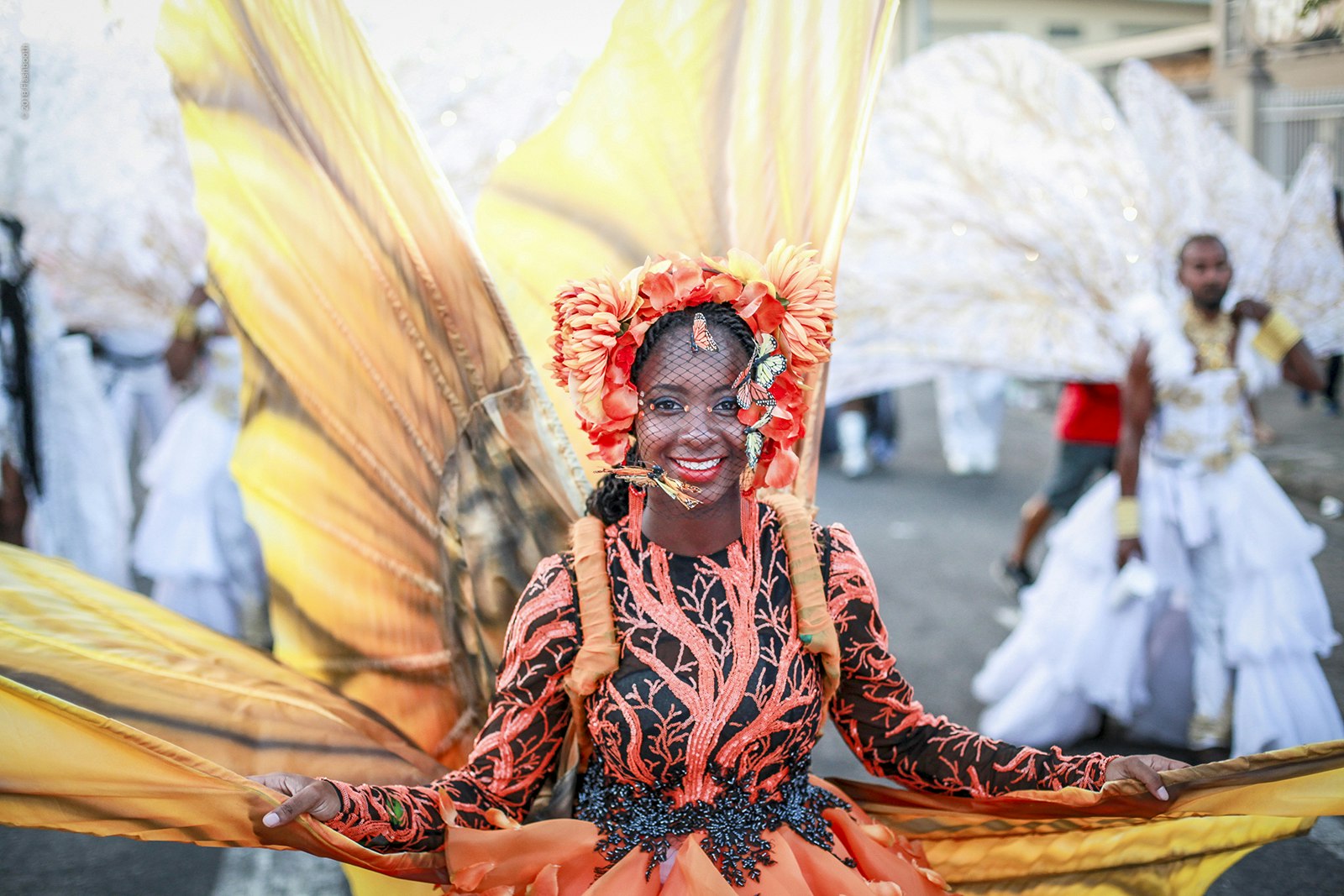 A woman in a traditional mas costume that resembles a sunflower spreads her petals at Carnival in Trinidad