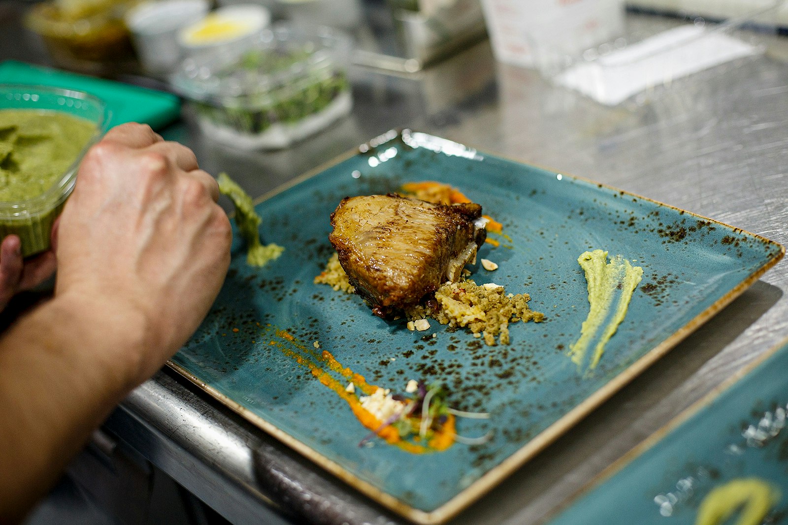 A person uses sauce as a garnish on a plate with cooked tuna. Cádiz, Spain.