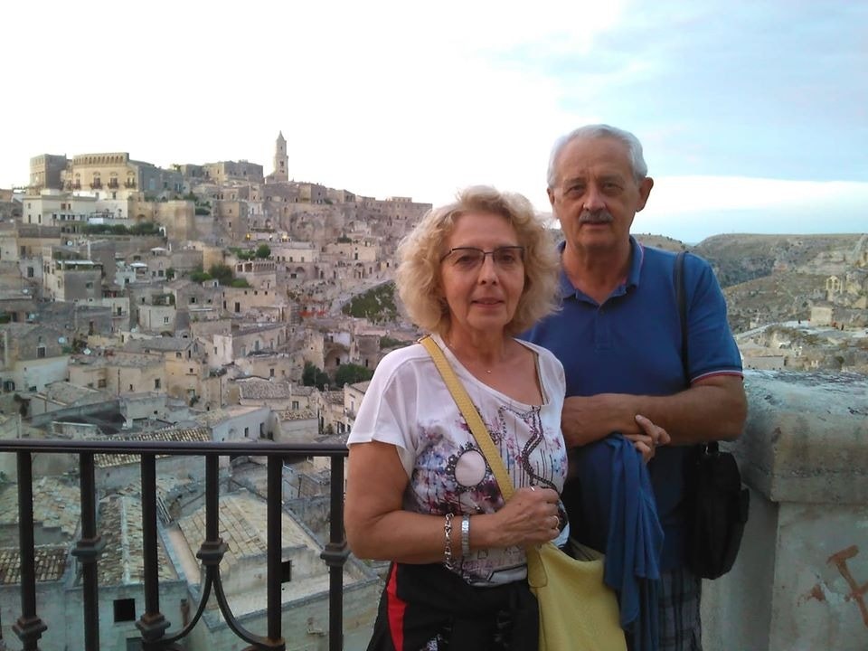 Marco's parents Tundra Sartorel and Maurizio Ferrarese stand side by side on a balcony overlooking the historic city of Matera in Italy
