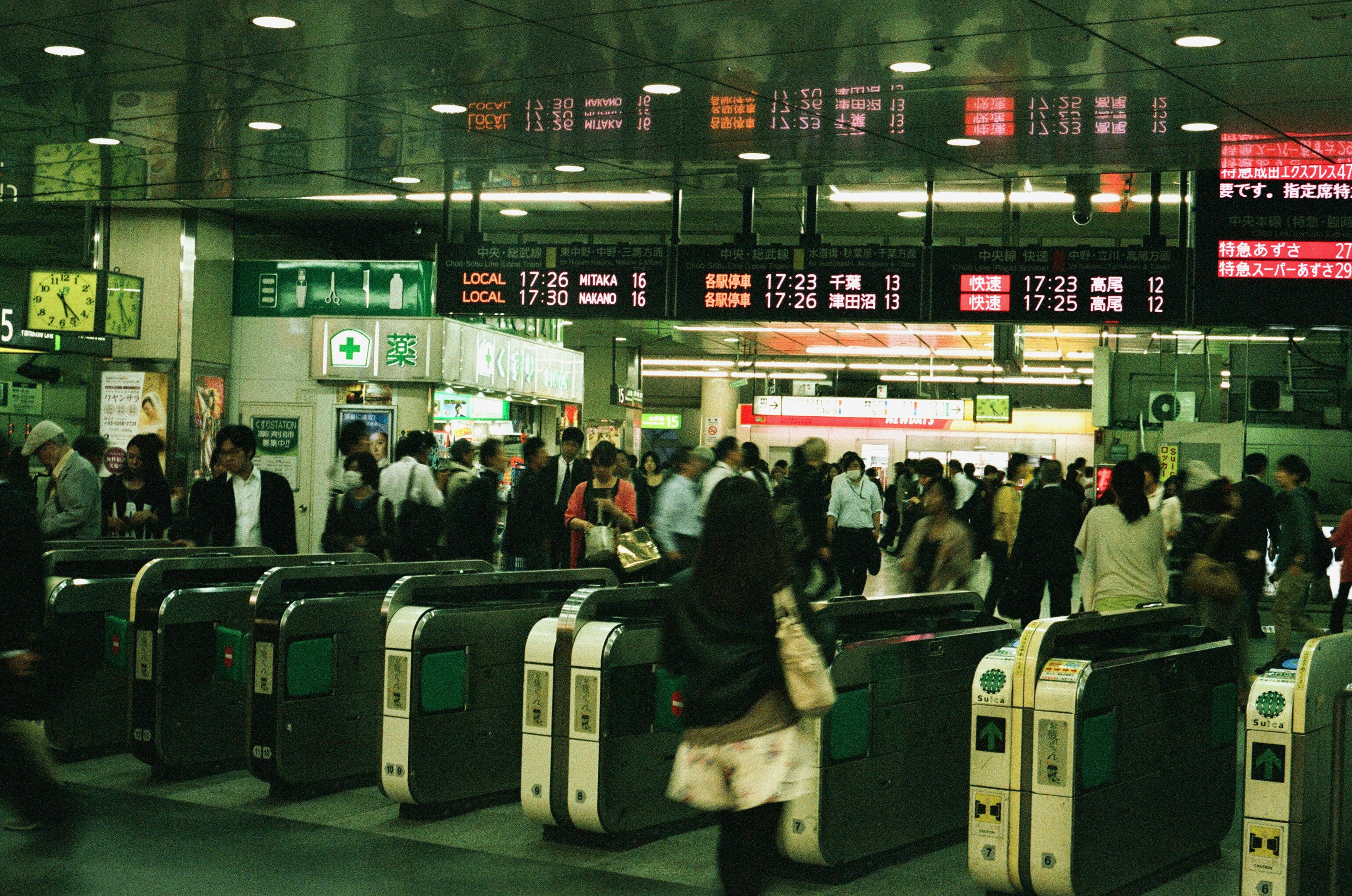 A crowd of people are going through the turnstile at Tokyo metro