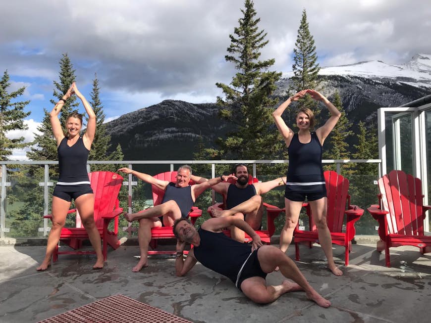 Människor gör galna poser bredvid en varm källa medan de bär fåniga baddräkter under vintern vid Banff och Lake Louise