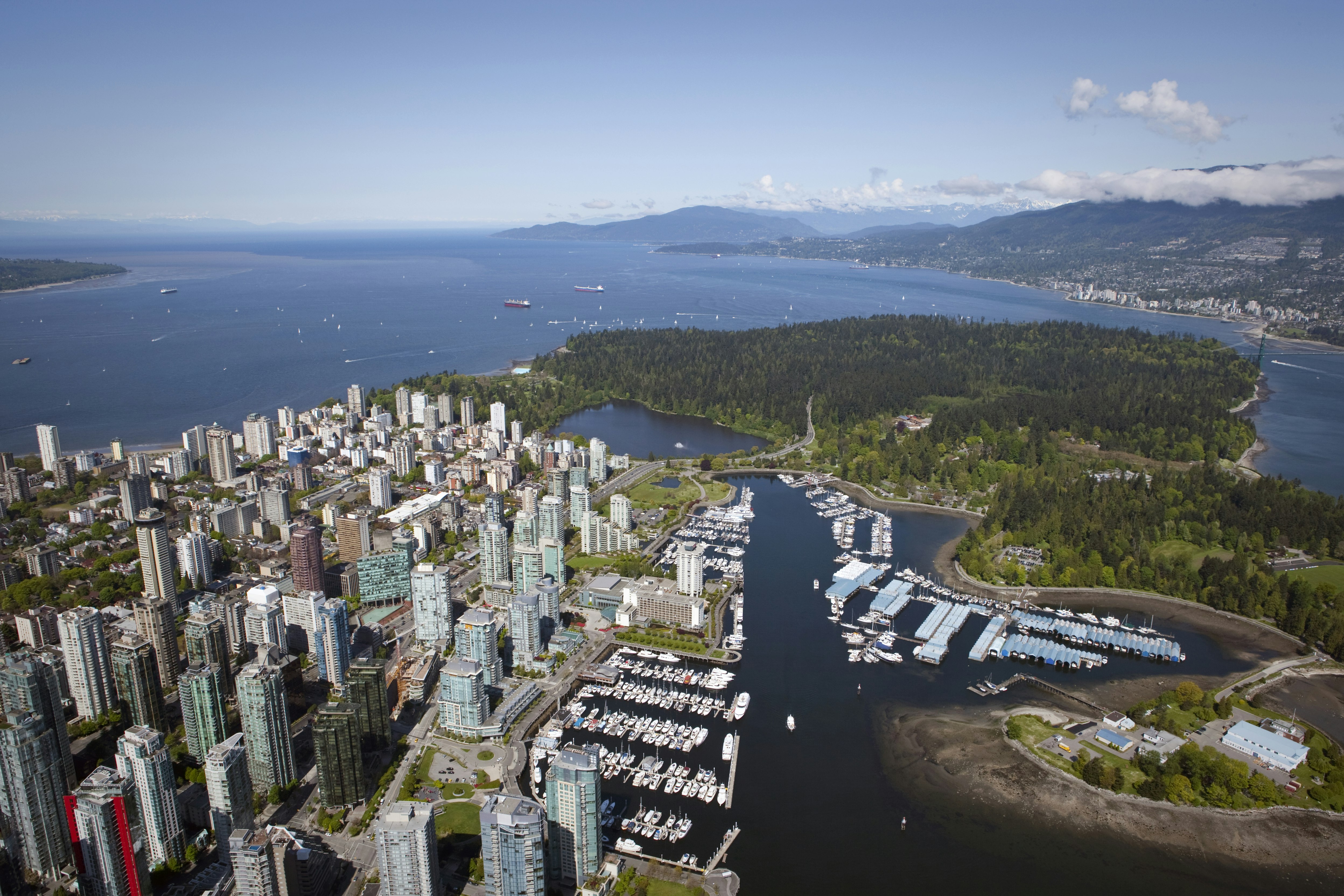 An aerial view of the city of Vancouver and Stanley Park, with harbors and buildings on one side connected to a wooded island with the sound in the background. The Vancouver Greenest City 2020 Action Plan is coming up on its target date.