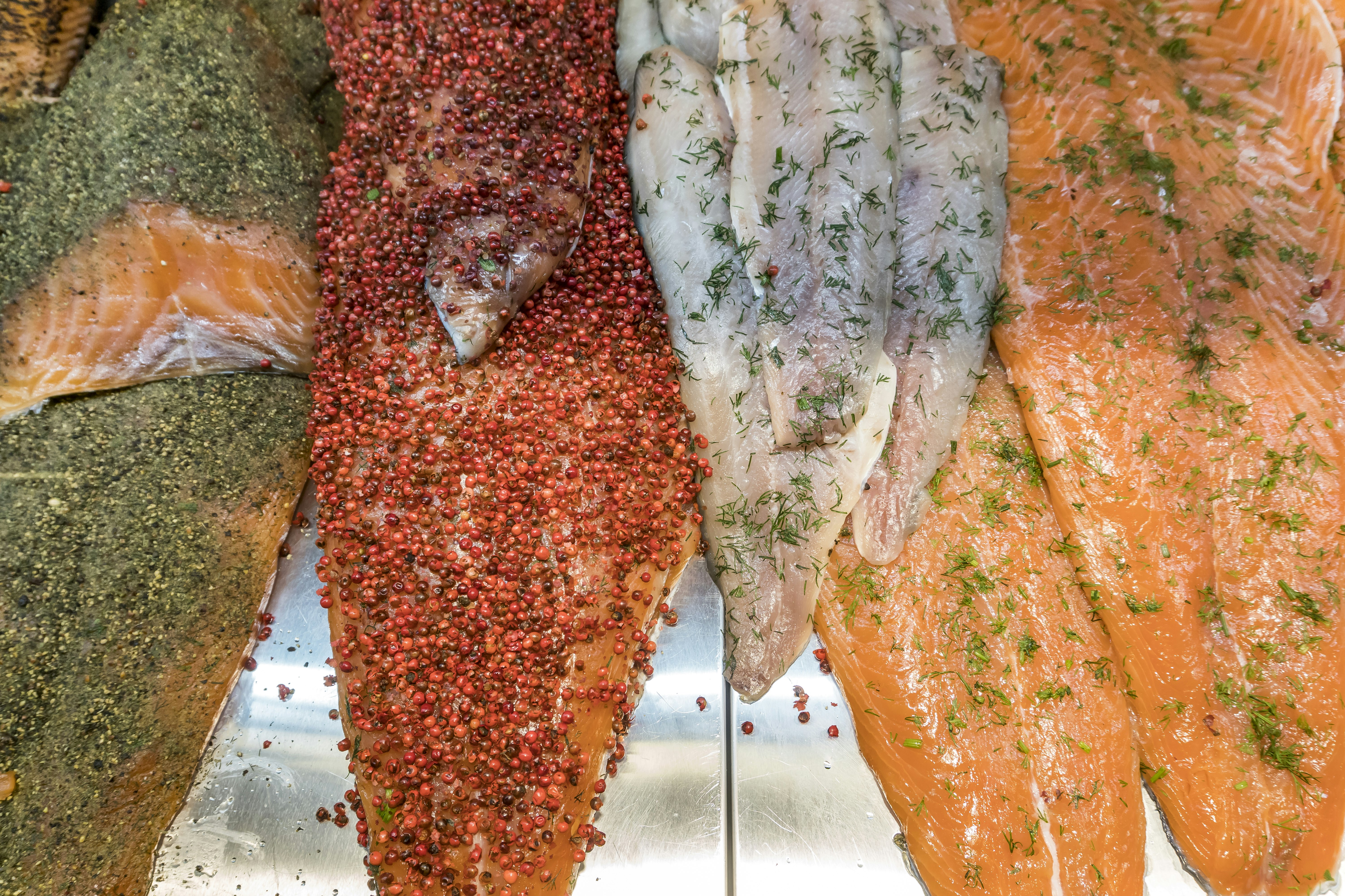Several fillets of fish have been coated with different colorful herbs and spices at Vanha Kauppahalli in Helsinki.
