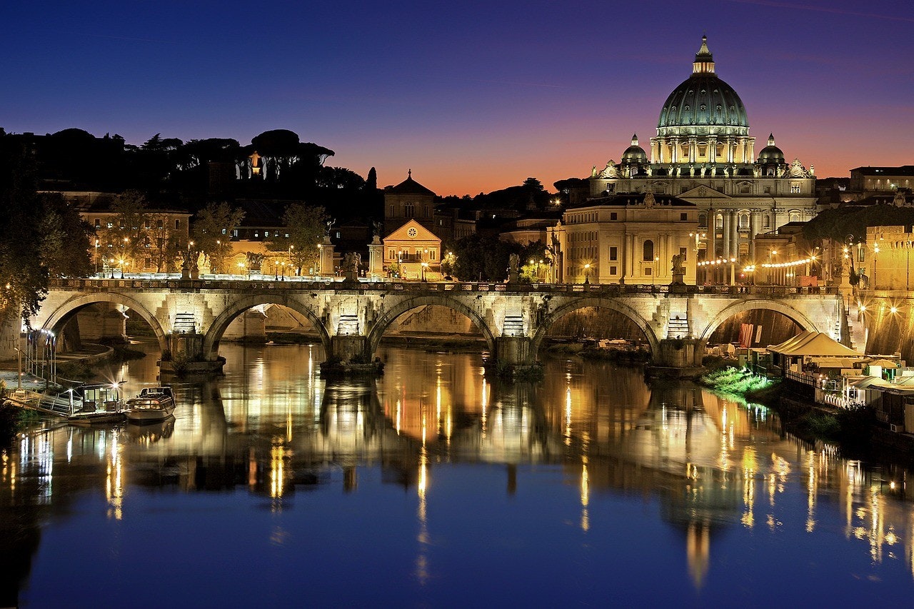 A view of Vatican City by night with a bridge and water