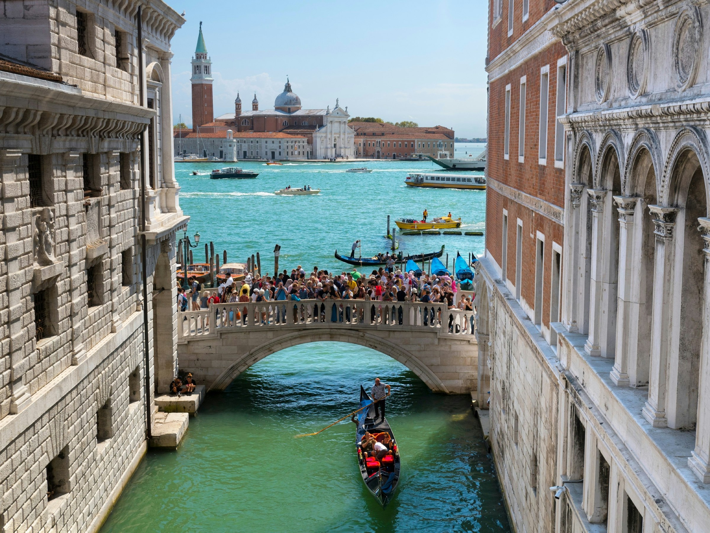 A gondola travels under the crowded Ponte della Paglia bridge in Venice. 