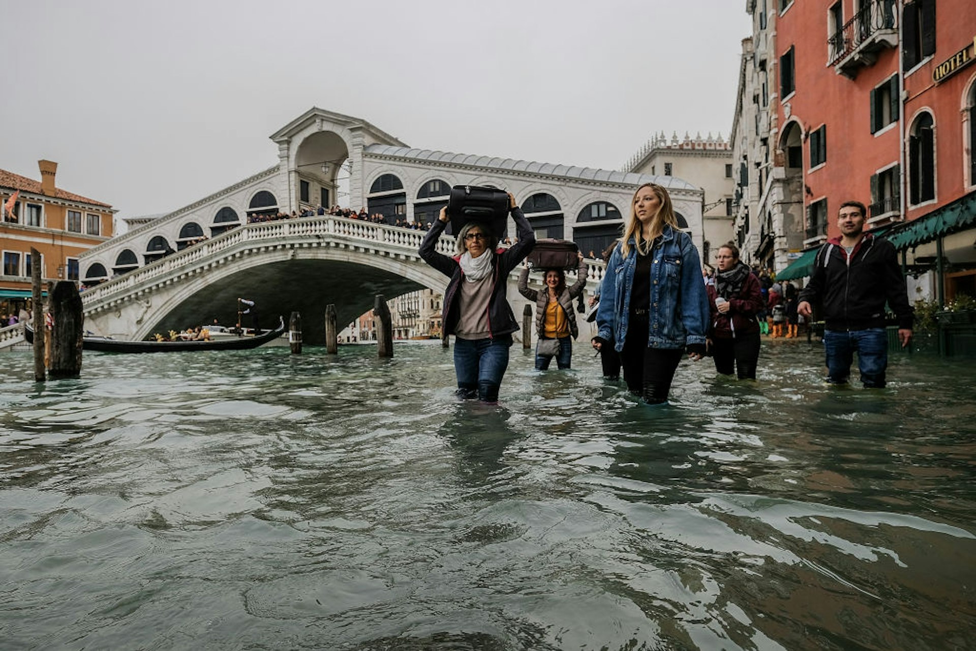 A tourist walks with her luggage over her head near the Rialto bridge in Venice floods