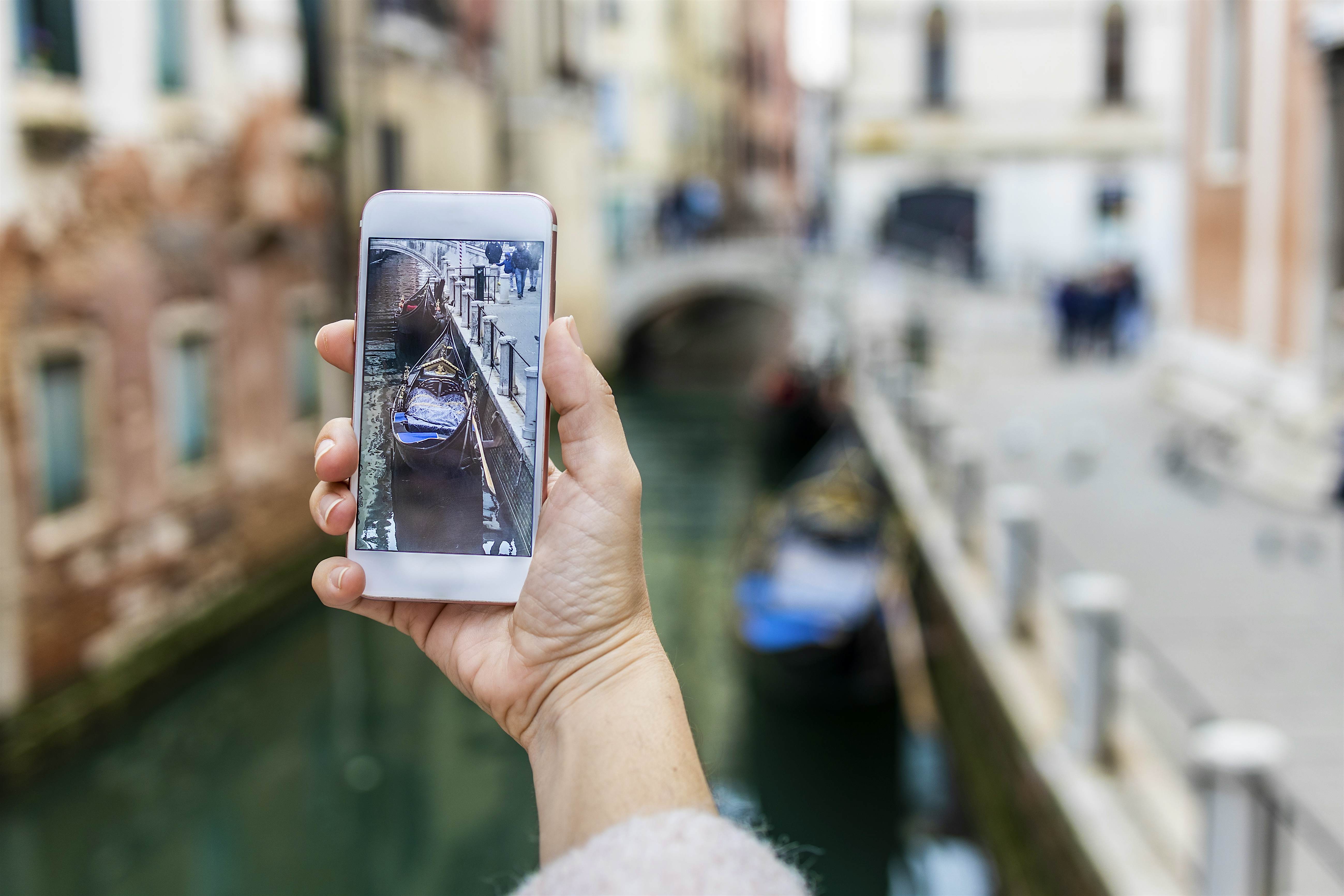 Mão cortada de mulher fotografando com telefone celular em Veneza