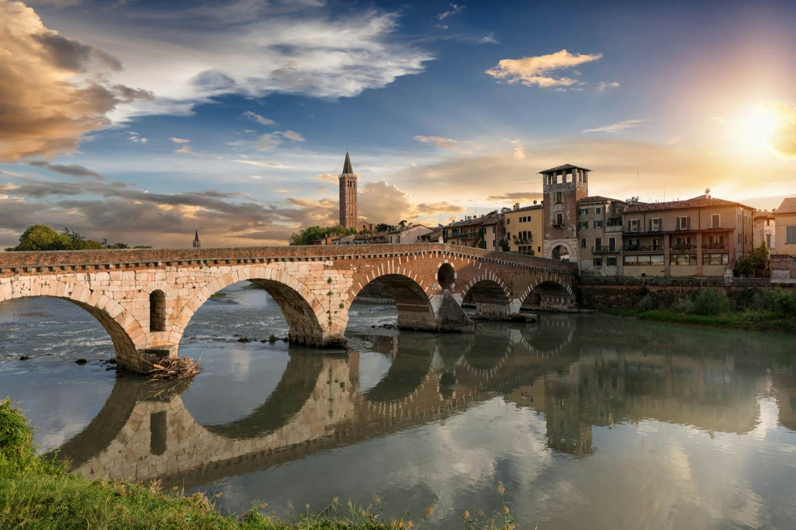 a stone bridge over a river leading to a medieval town 