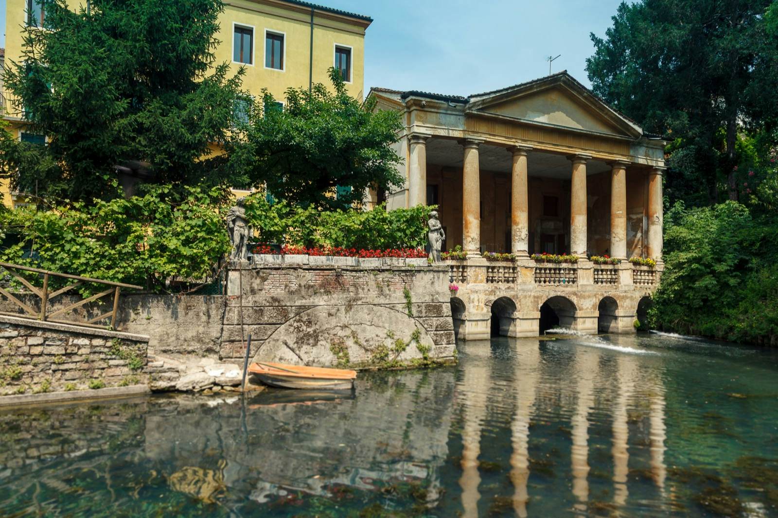 A canal runs past a stone house with a little row boat tied up in front