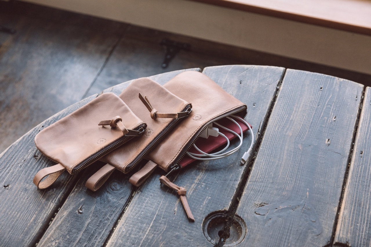 WP Standard pouches in tan, on a table - one open with charging cable and notebook showing