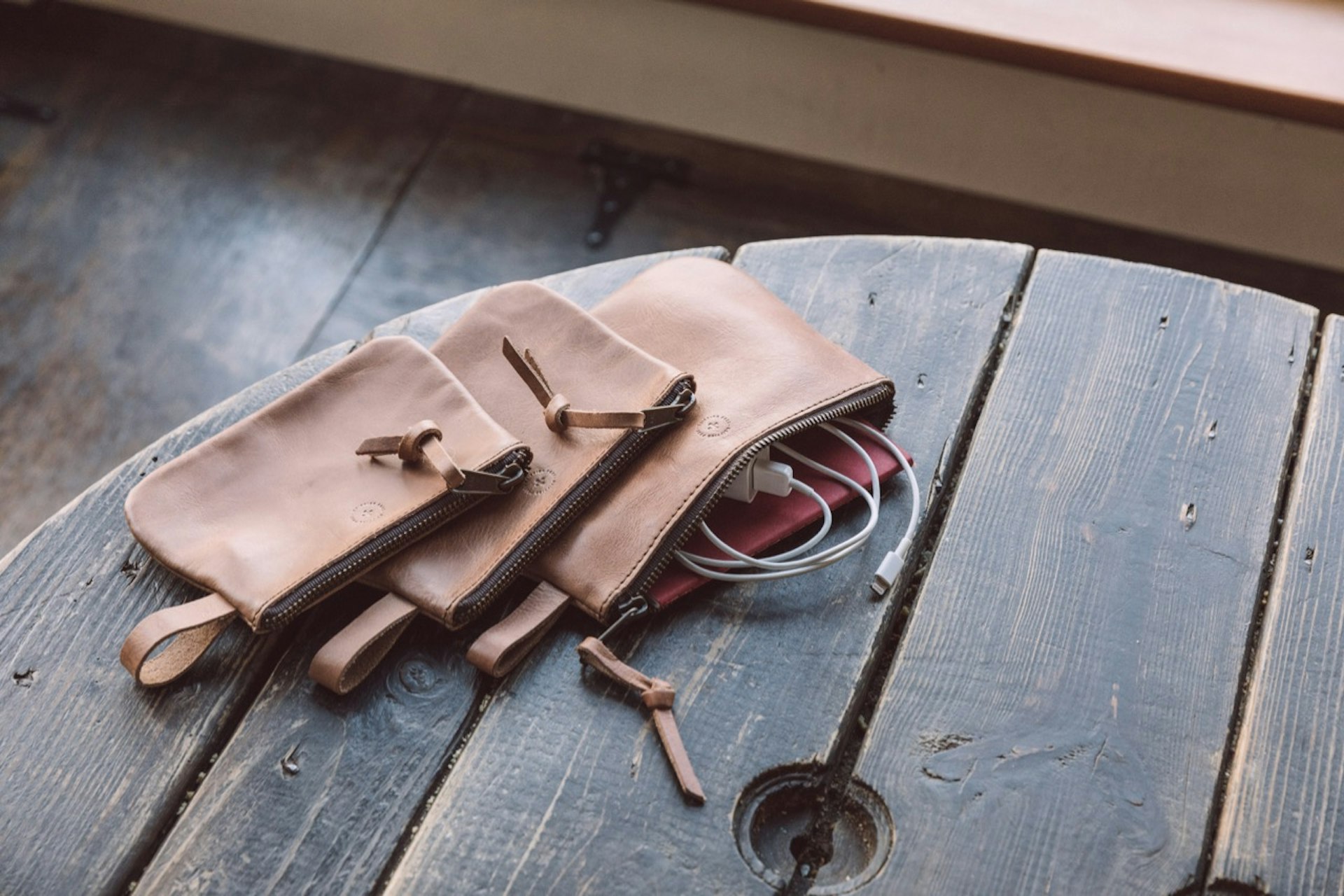 WP Standard pouches in tan, on a table - one open with charging cable and notebook showing