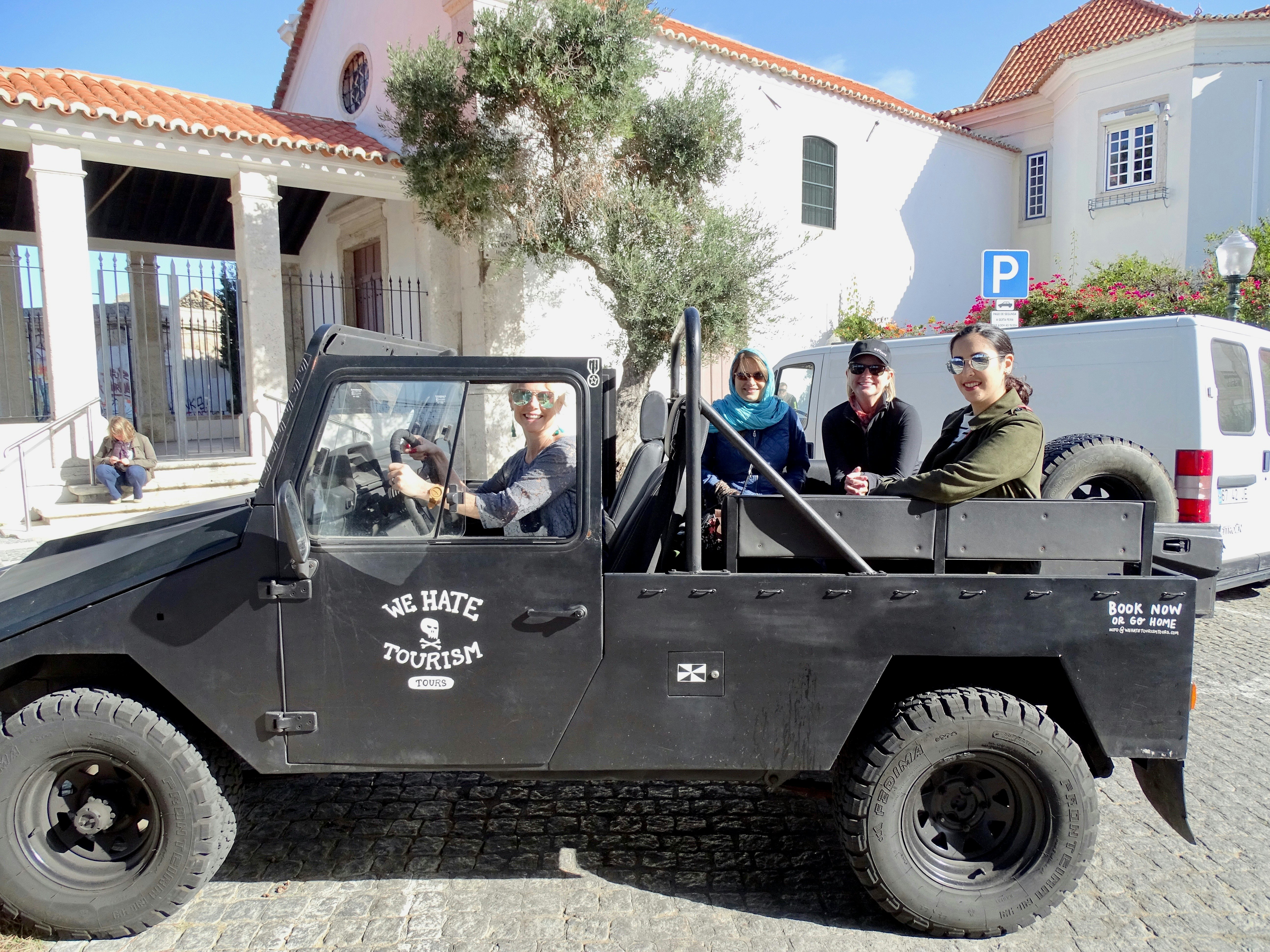 A black open-top jeep in Lisbon with "We Hate Tourism" stamped on the side.