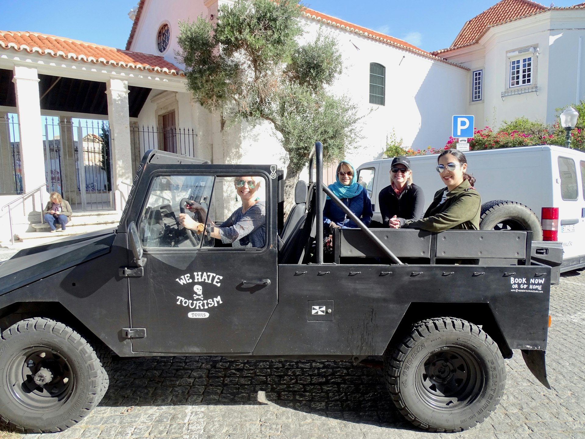 A black open-top jeep in Lisbon with "We Hate Tourism" stamped on the side.
