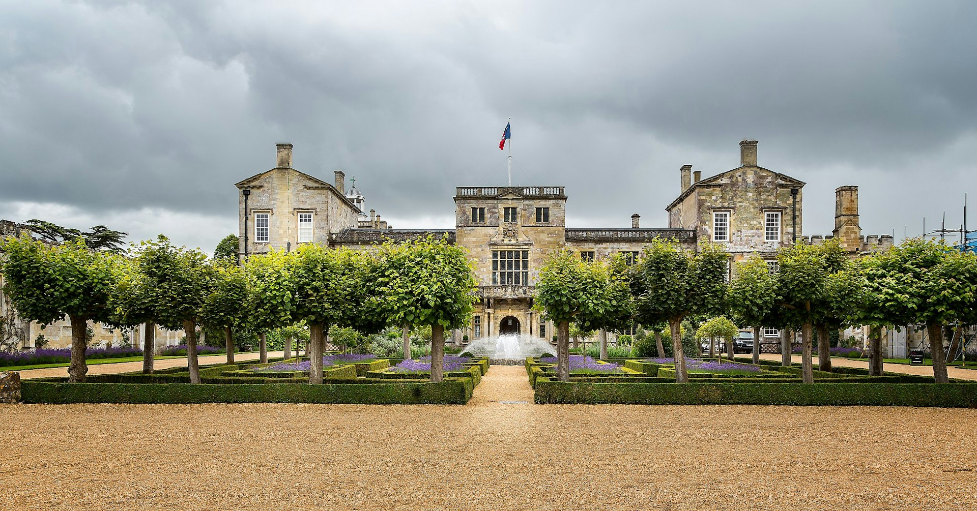 Wilton House, a stone neoclassical mansion, with a garden full of frees in front of it. 