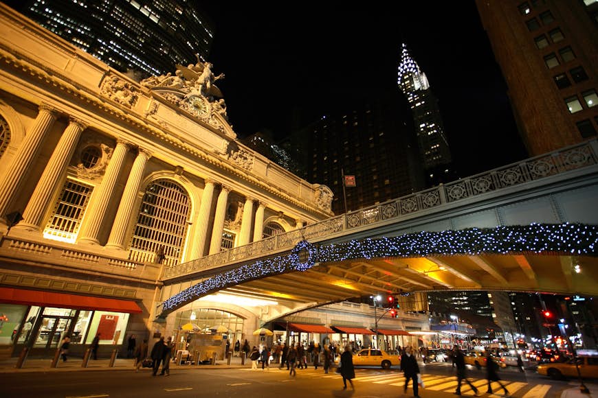 Julbelysning och en krans lyser runt utsidan av New York Citys Grand Central Station på natten