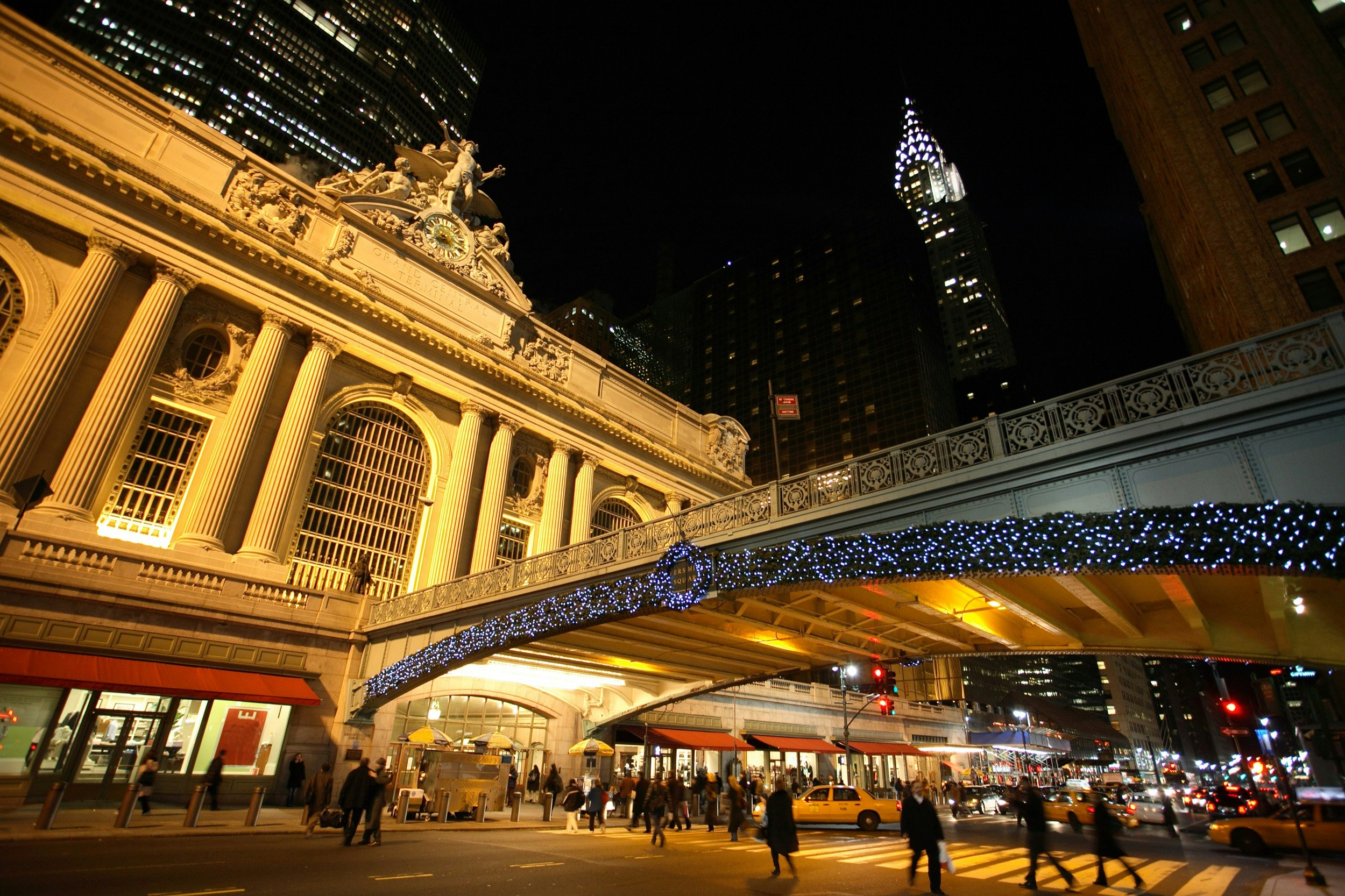 Christmas lights and a wreath shine around the exterior of New York City's Grand Central Station at night
