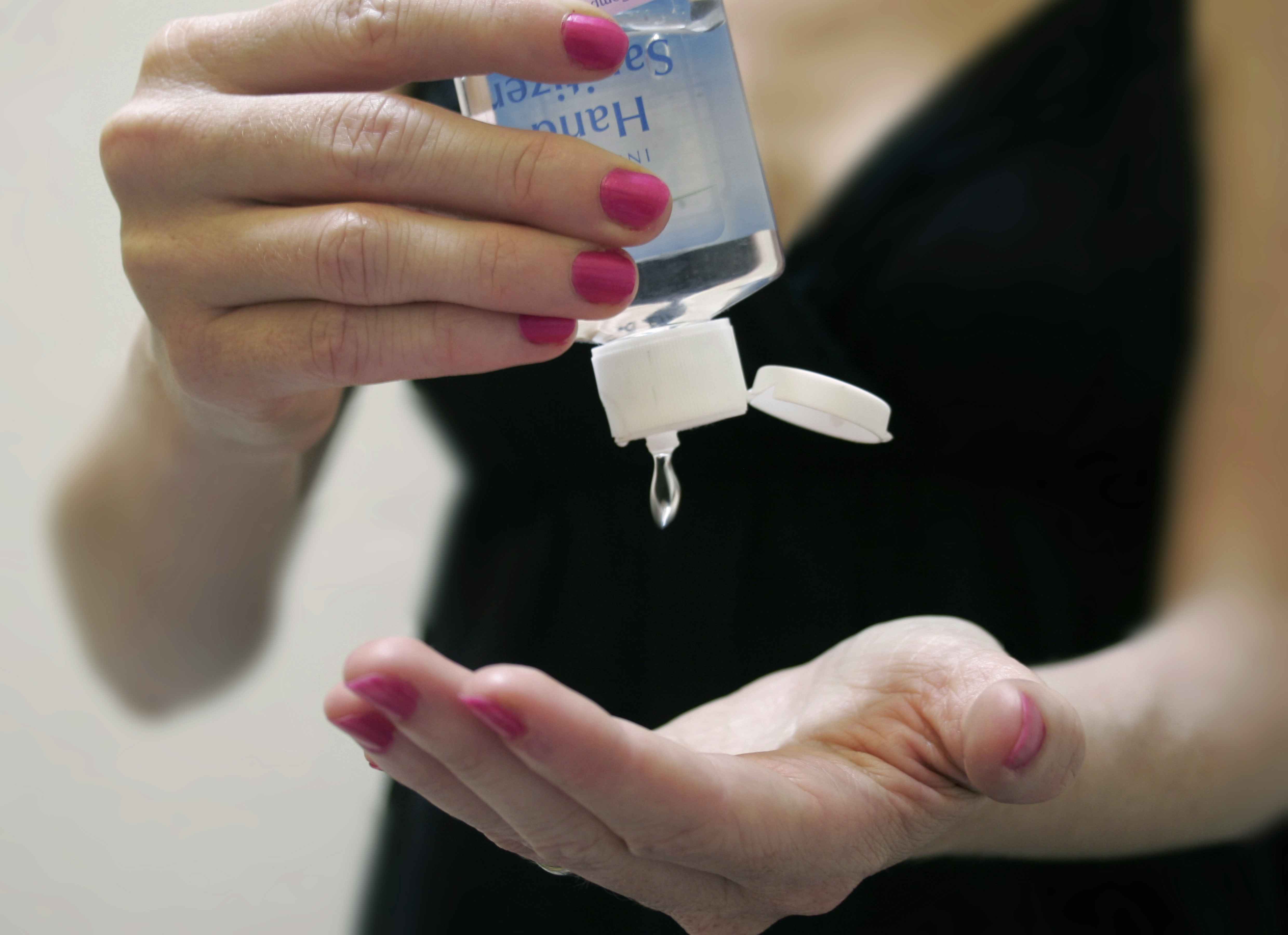 Closeup on hands of a woman applying hand sanitizer