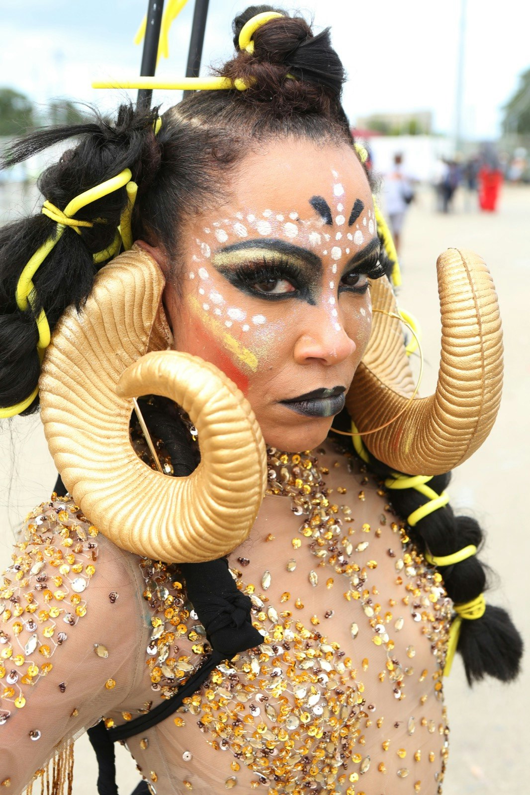 Woman in elaborate gold makeup with horns depicting a ram