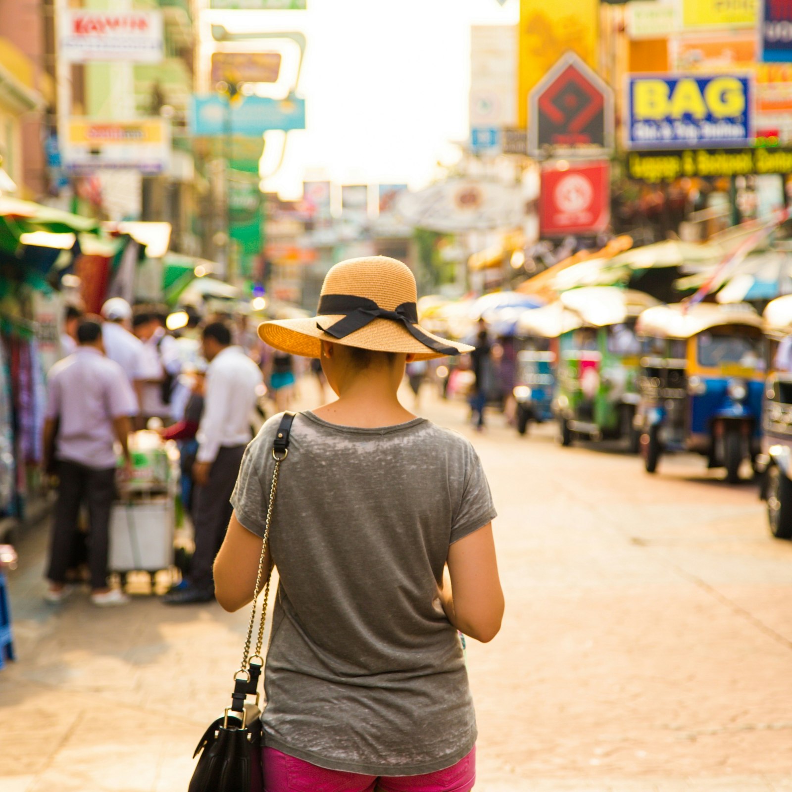 A woman with a hat walking along a shopping street in Bangkok