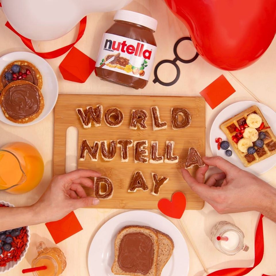 Top view of a table with hands holding letters that form the words "World Nutella Day"
