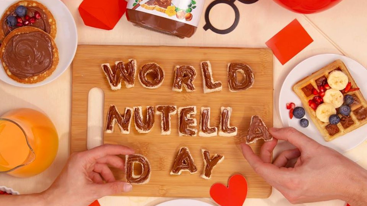 Top view of a table with hands holding letters that form the words "World Nutella Day"