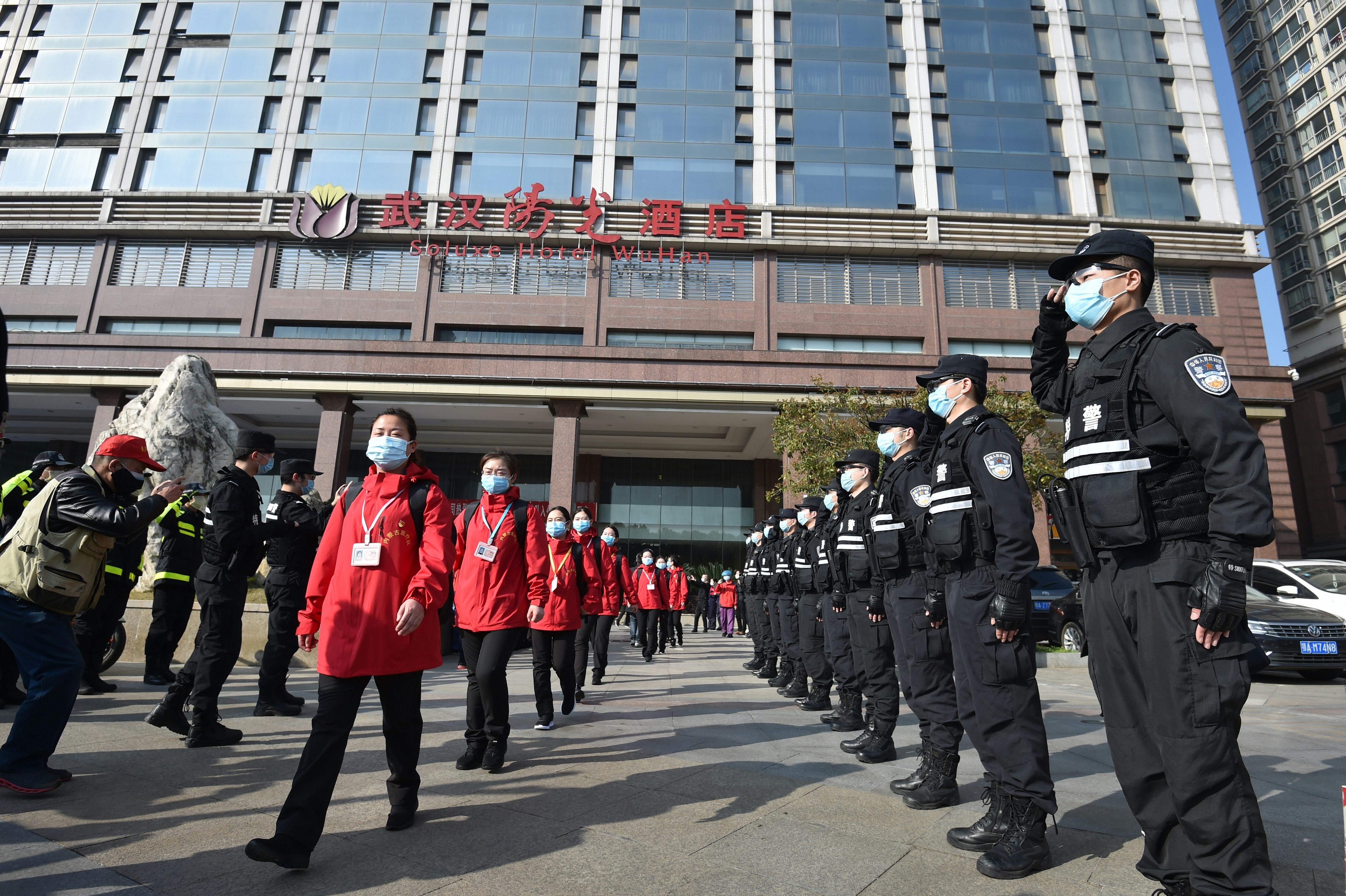 Chinese police are saluting medical staff as they march out of their hotel during the coronavirus pandemic
