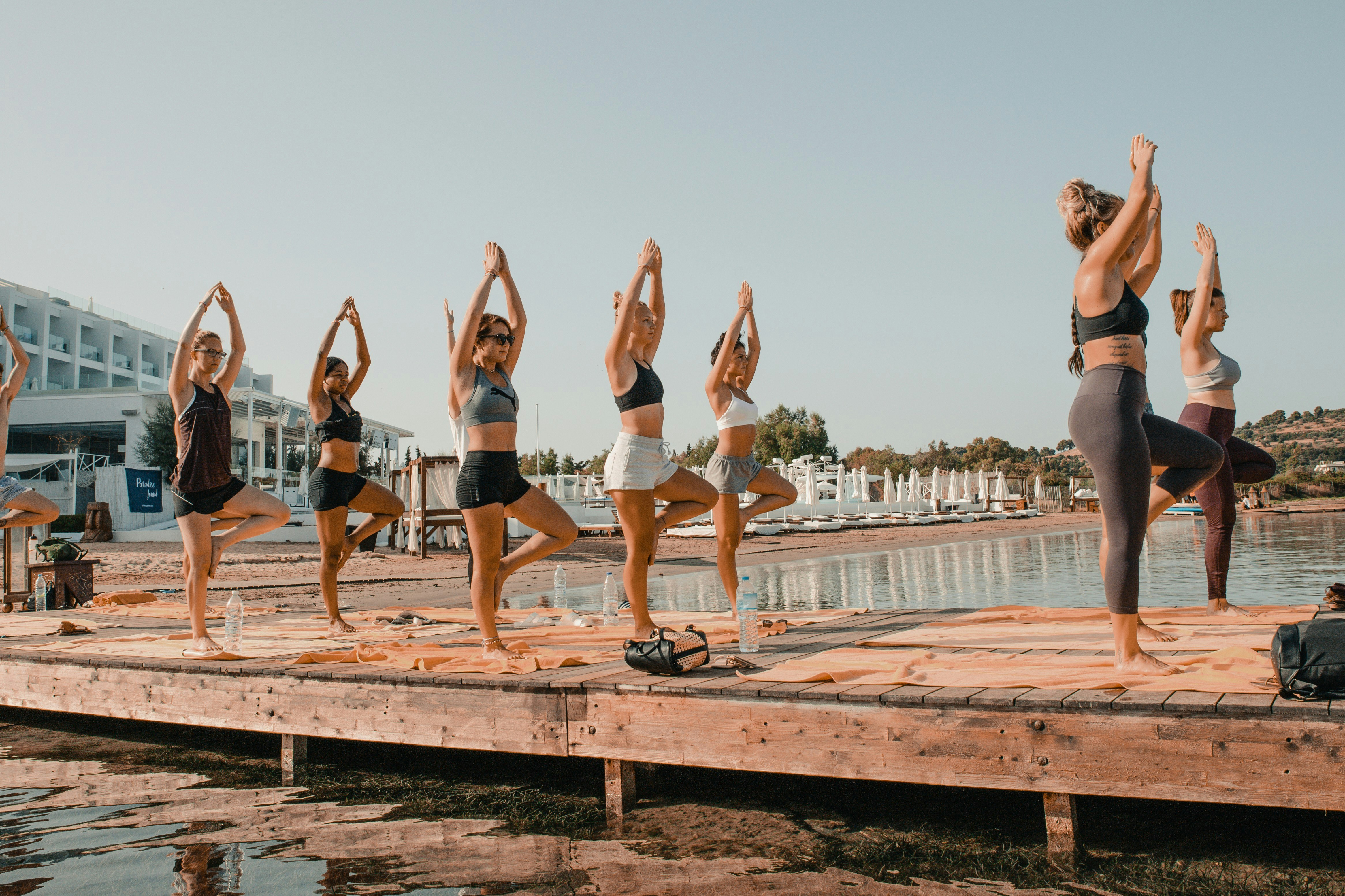 A group of women doing yoga on a walkway beside a marina