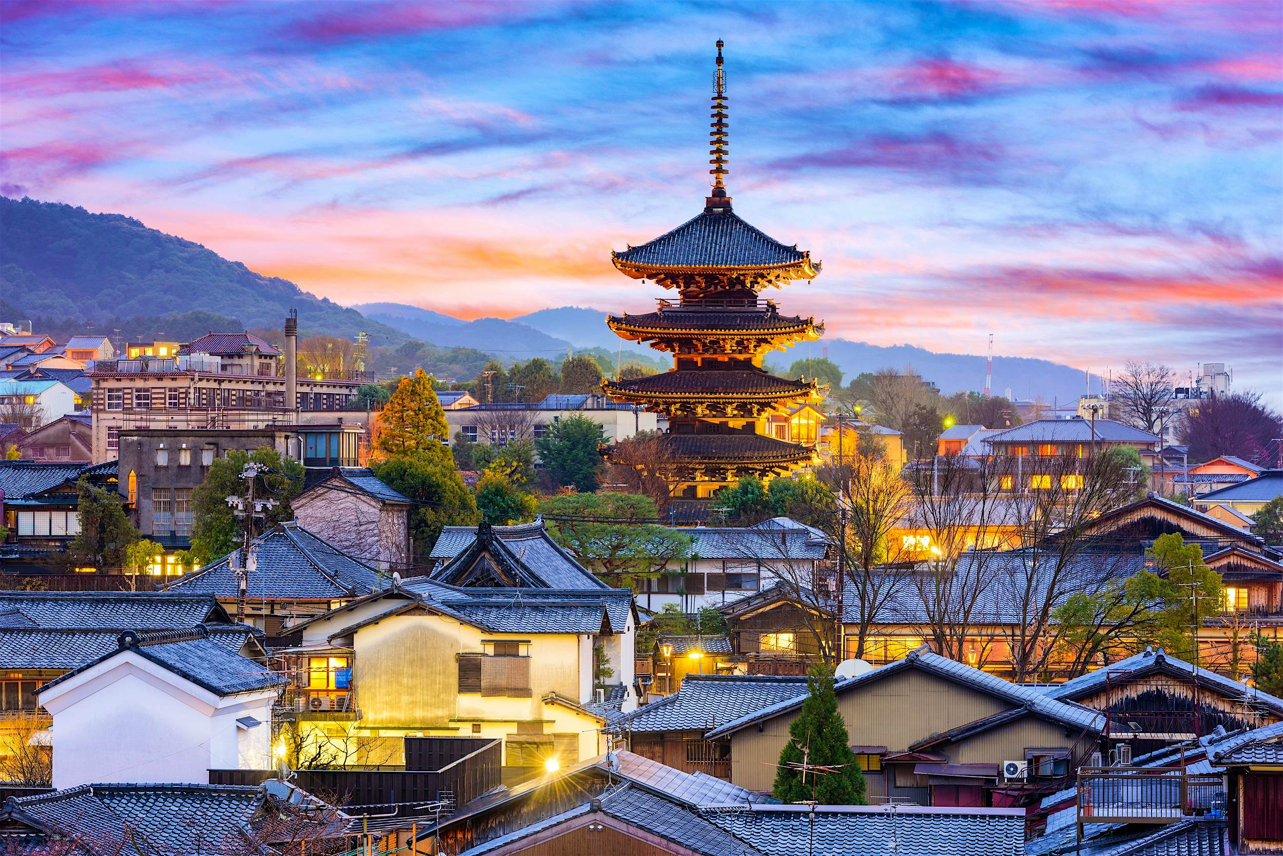 Rooftops and a towering shrine rising into the sky at sunset within Higashiyama
