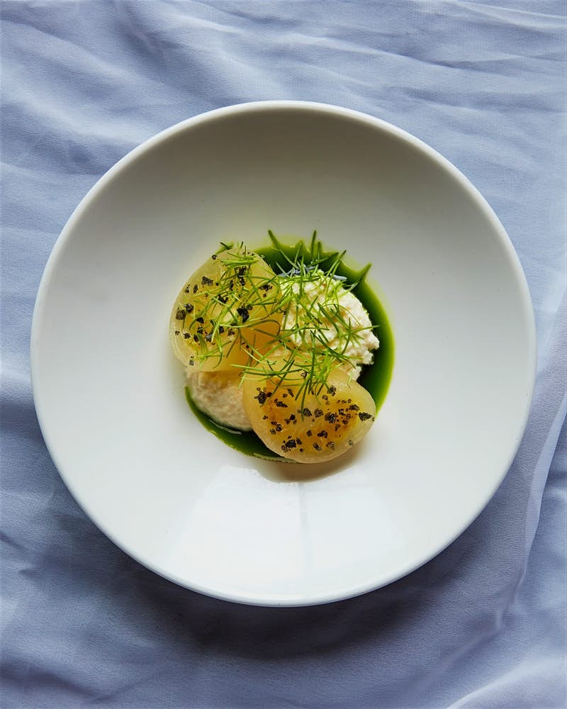 Yellow tomato sits on a white plate. 