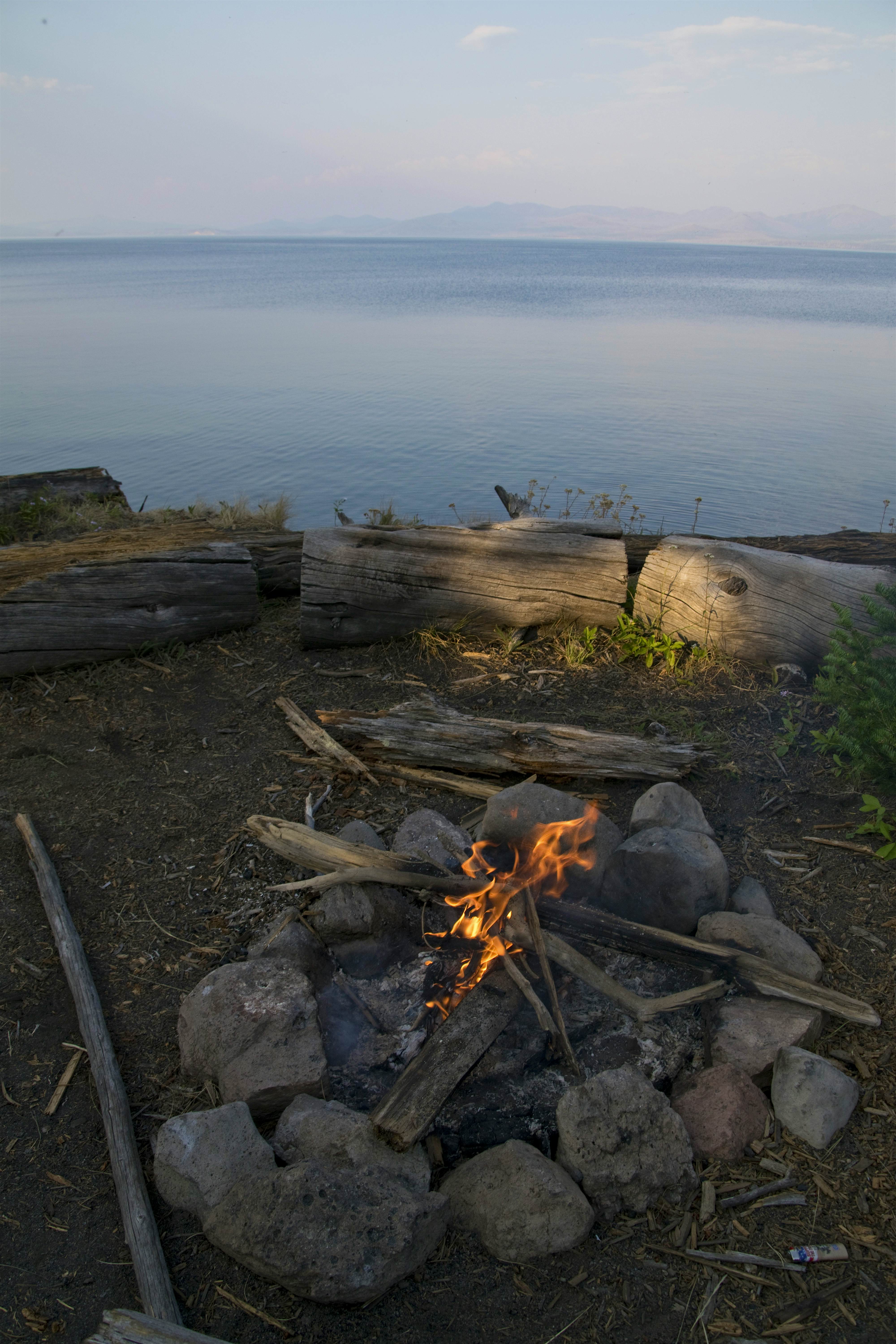 An open fire at a campsite in Yellowstone National Park, near a lake suitable for paddling