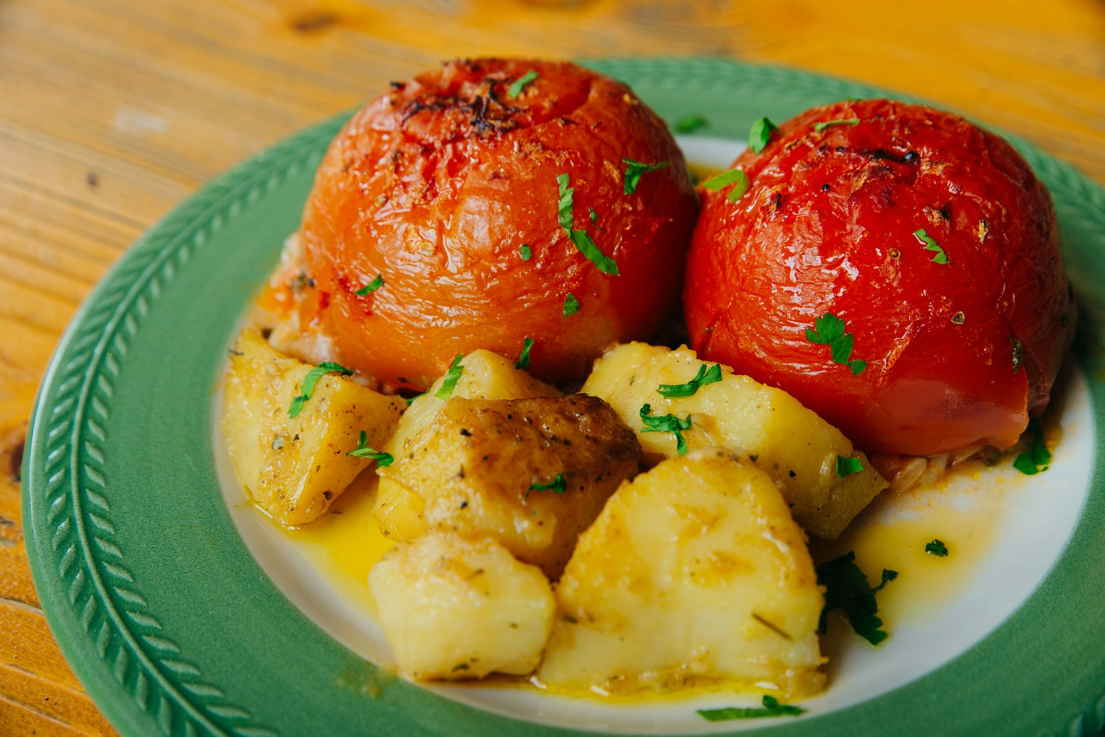 Yemista, stuffed tomatoes with potatoes served on a patterned, blue ceramic plate