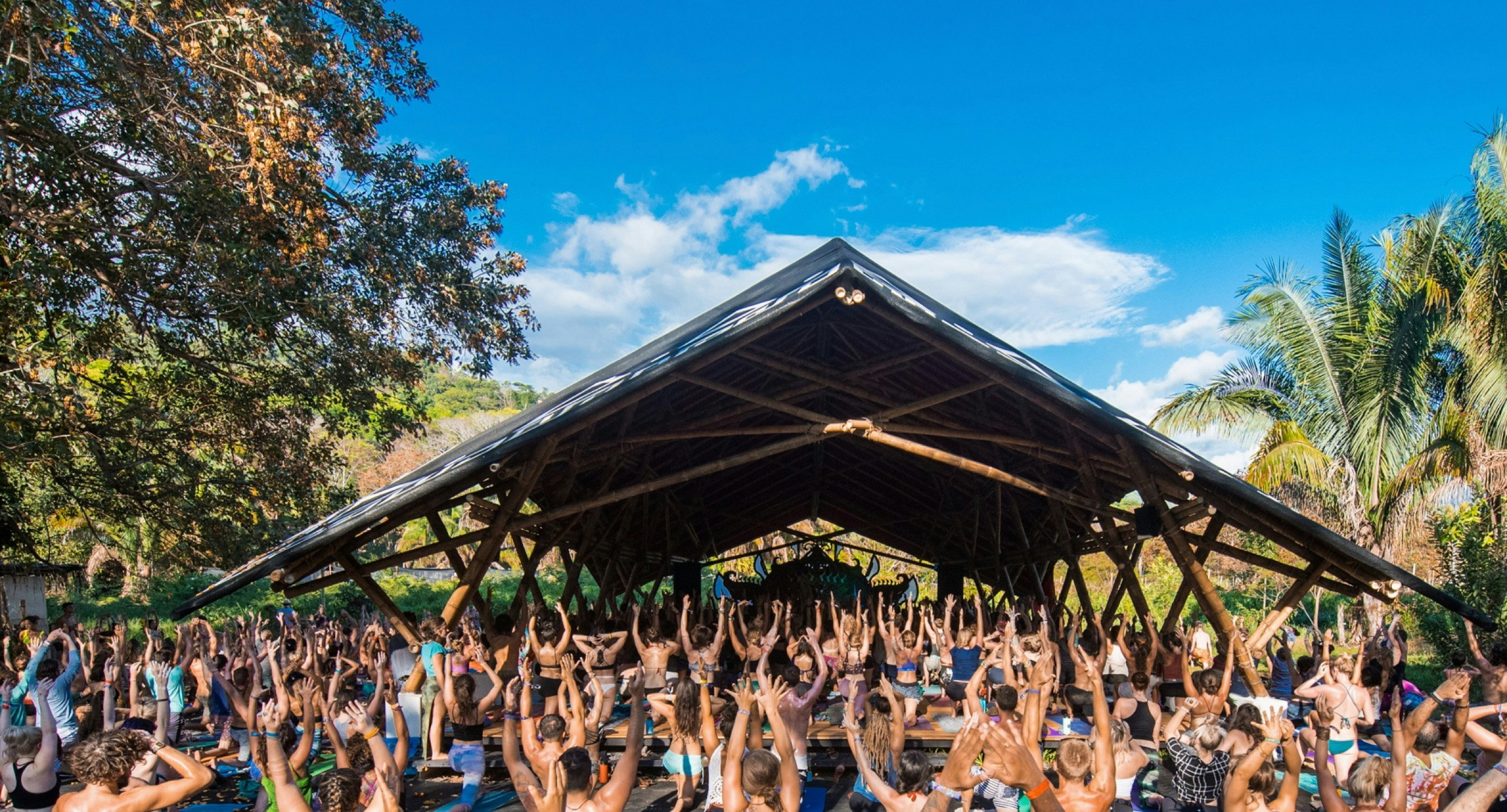 Hundreds of people do yoga exercises in front of an a-frame temple in Costa Rica