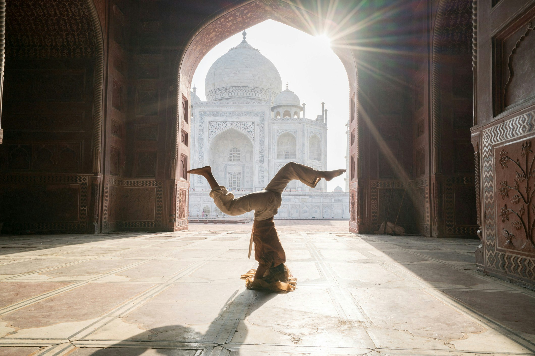 A woman practising yoga in India at the Taj Mahal at sunrise 