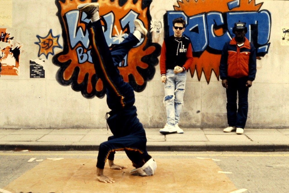 Z Boys breakdancing before street art on a wall